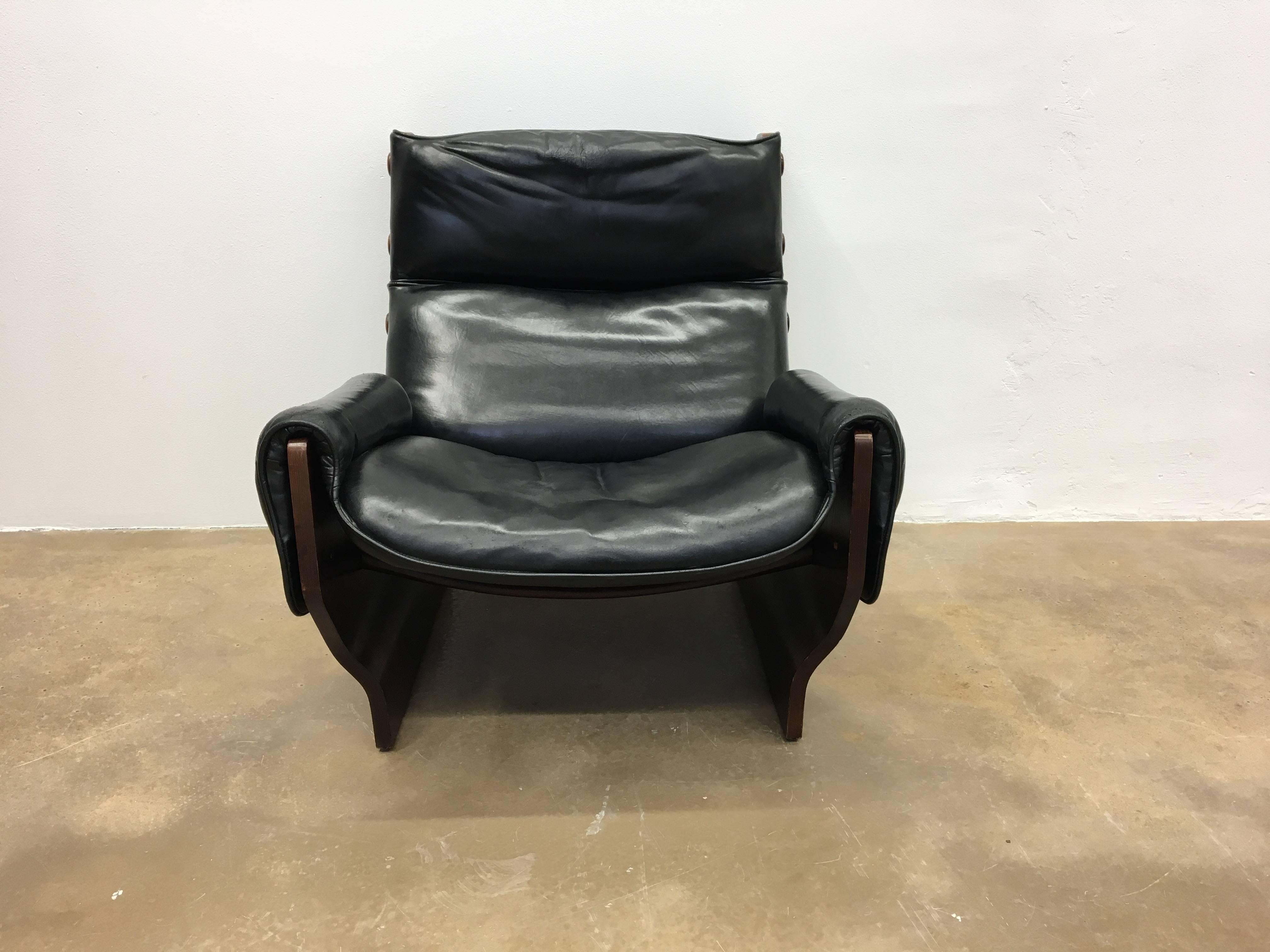 Osvaldo Borsani for Tecno, lounge chair 'Canada' T110, in plywood and black leather, Italy, 1960s. The 'Canada' chair is composed of two sides made of moulded plywood connected by two contoured solid wood crosspieces made of teak. Upholstered in