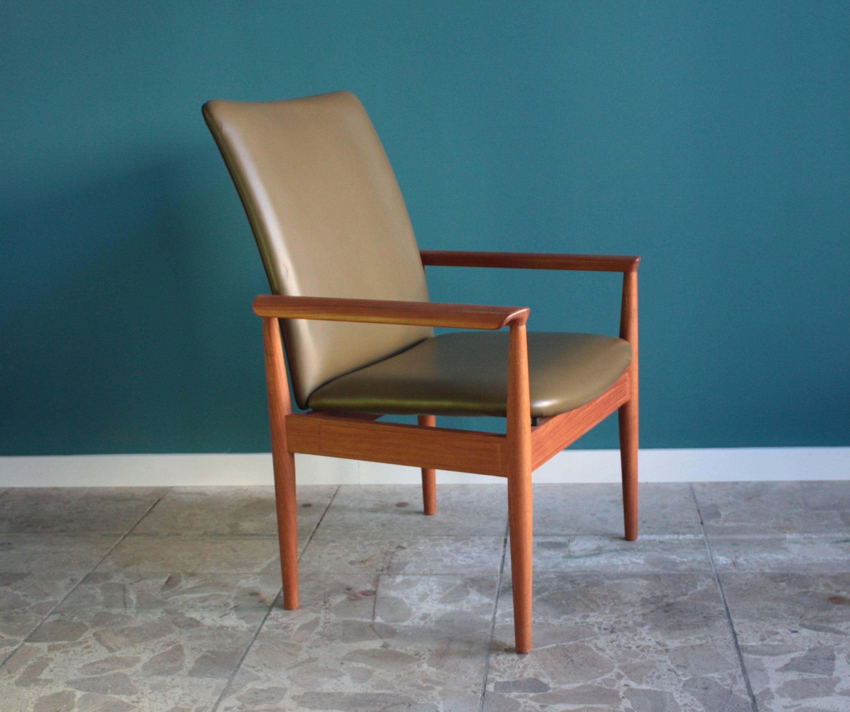 This Diplomat chair was designed by Finn Juhl. It was manufactured by Cado and features a frame made from teak. The chair is upholstered in olive green leather and has a high and flexible backrest. It is in a very good vintage condition.