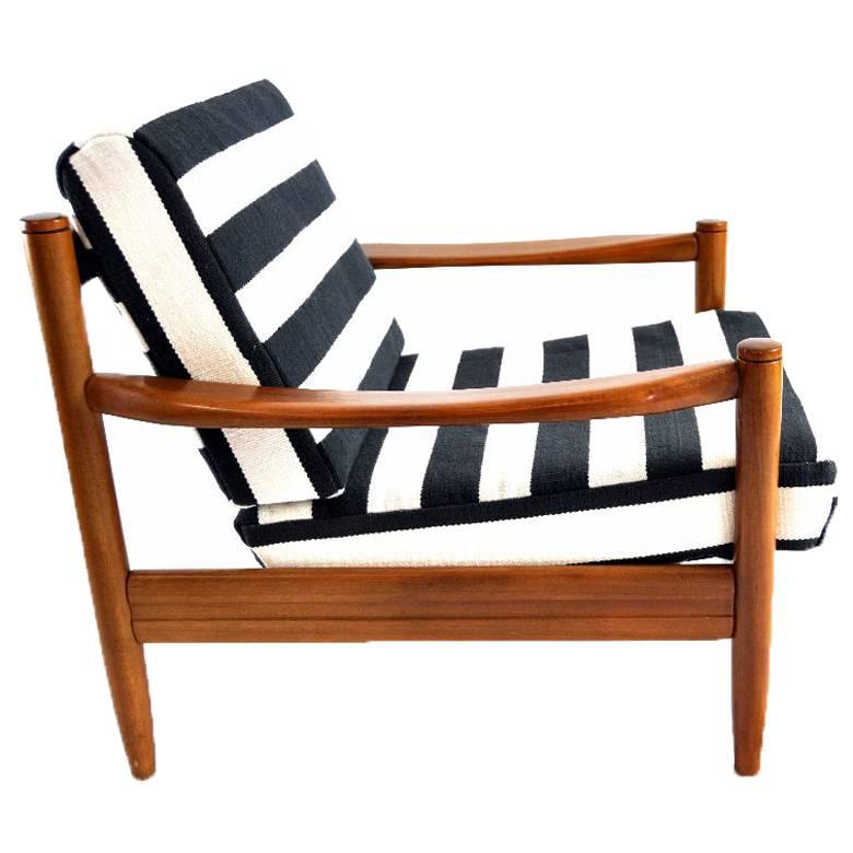 This lounge chair was manufactured in the 1960s in Denmark. It is made of solid teak and features cushions upholstered in black and white striped Kilim fabric. The covers are removable.