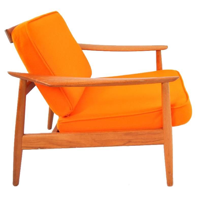 This chair was designed by Arne Vodder in the 1960s and was manufactured by France and Son in Denmark. It is made of solid teak and the back legs are slanted so that the seat is slightly sloped. The cushions have been covered in orange wool felt.