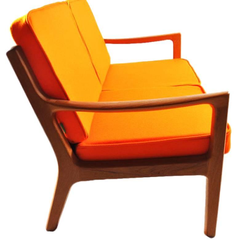 This senator two-seat teak sofa was designed during the 1960s by Ole Wanscher for Poul Jeppesen in Demark. It is upholstered in orange woolen felt.