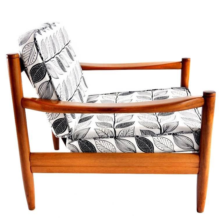 This lounge chair was manufactured in the 1960s in Denmark. It is made of solid teak and features cushions upholstered in a leaf print jacquard fabric. The covers are removable.