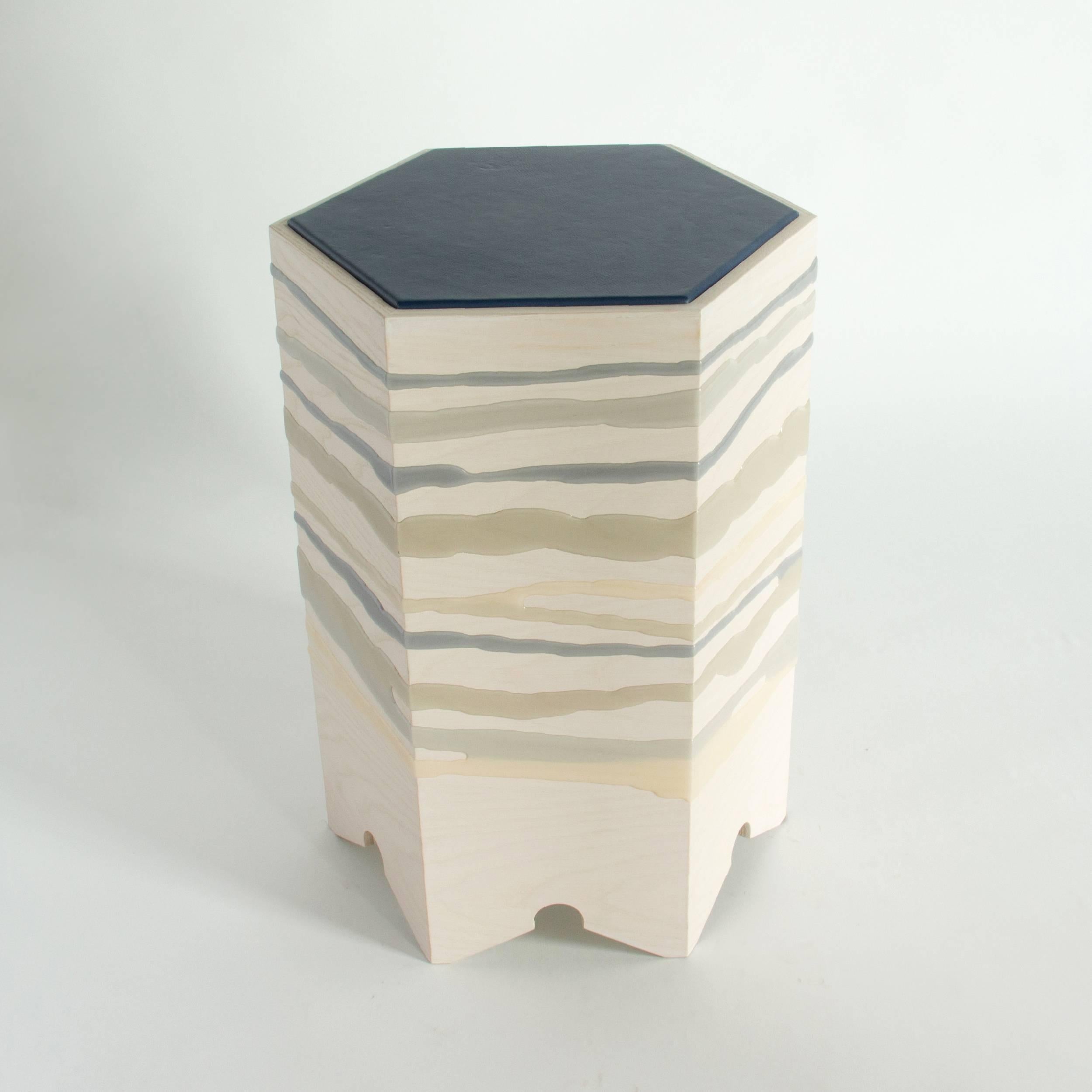 The drip/fold side table by Noble Goods is constructed of a single sheet of ash plywood that has been hand-dripped with liquid resin, and then bent into a hexagonal shape. Finished with a leather upholstered top. The distinct but overlapping blues
