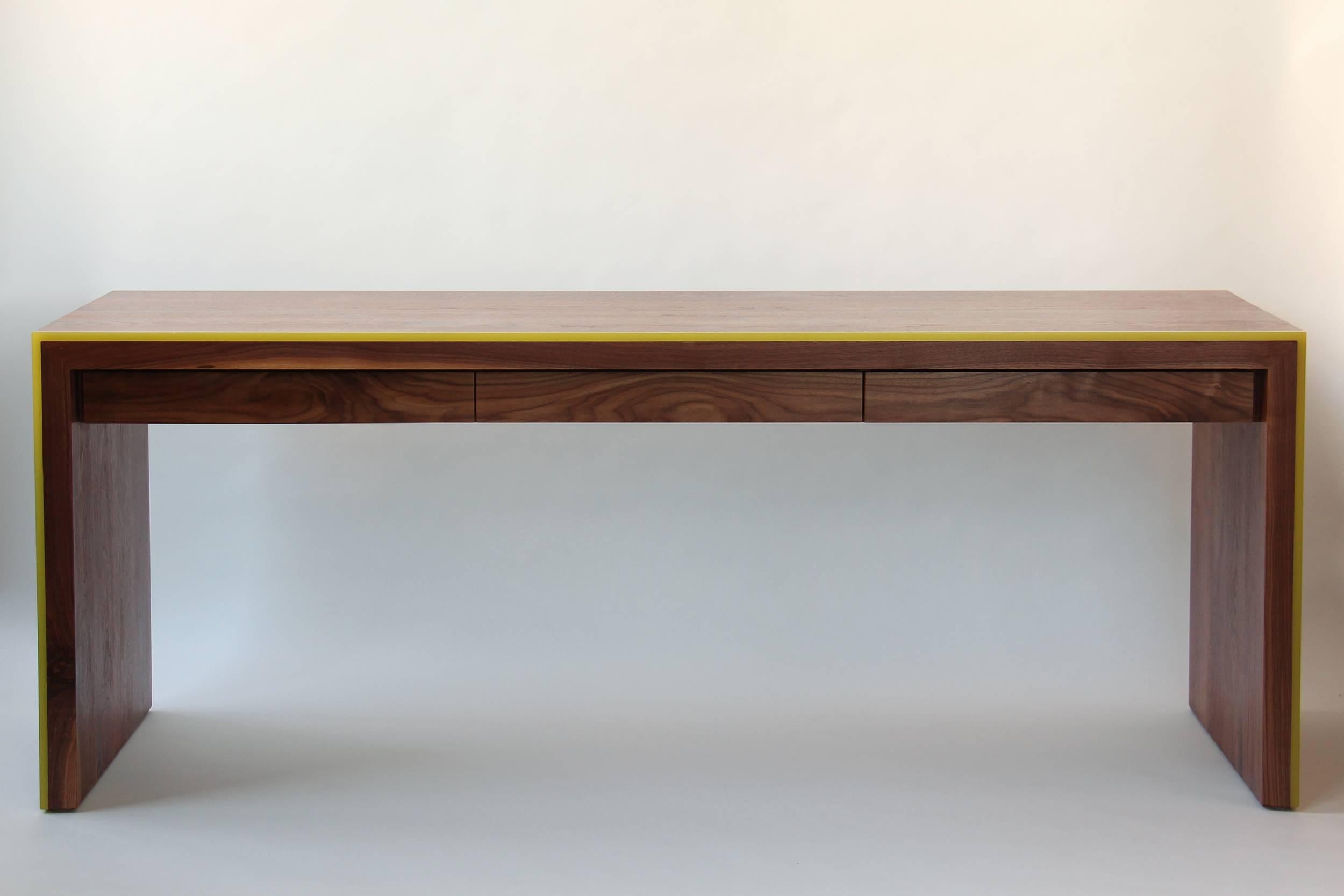 The simple form of the waterfall design highlights the beautiful wood grain of this solid walnut desk, while the sleek band of brightly colored resin plays off the rich color, making it appear as though it's lit from within. Three slender drawers,