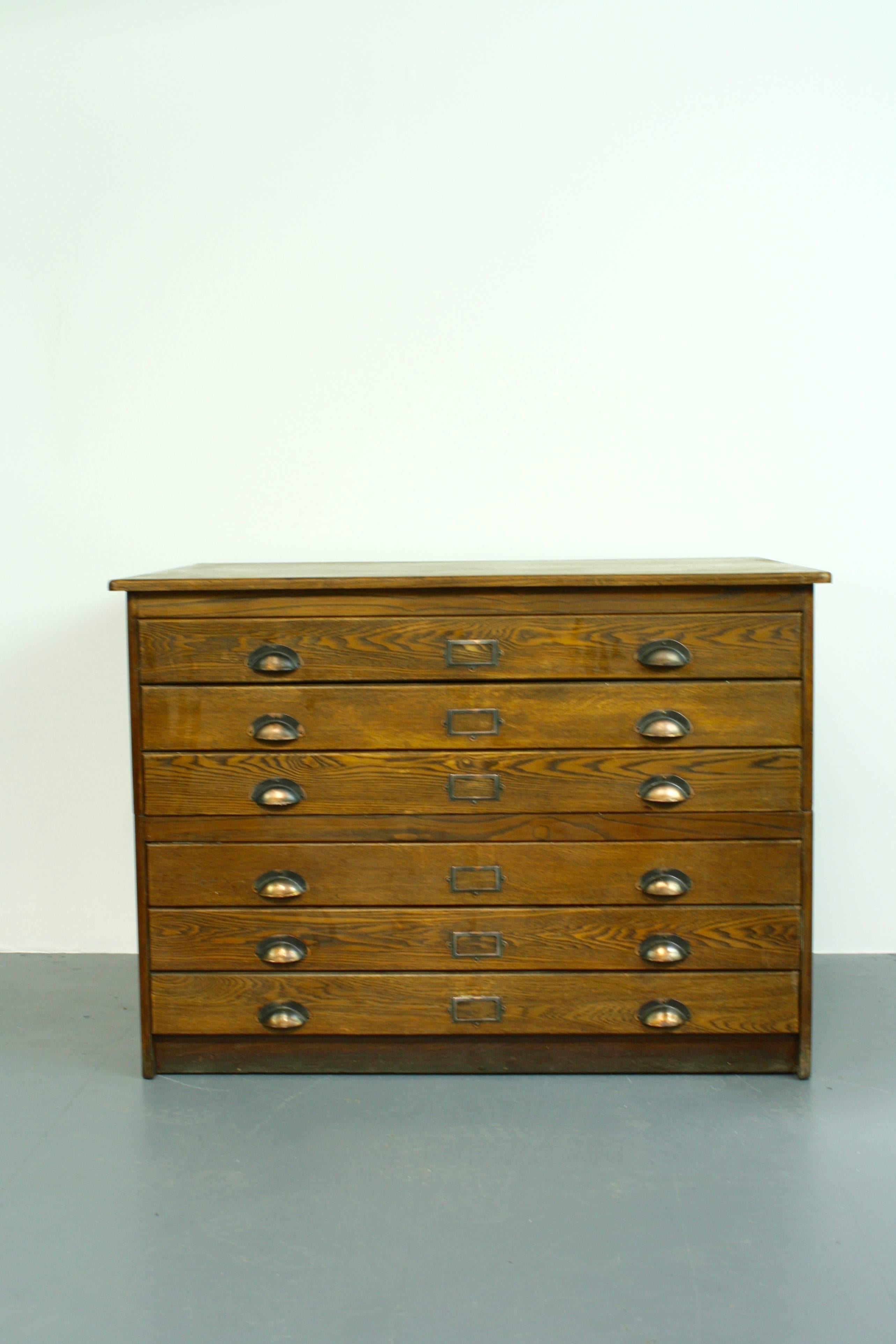 A six-drawer vintage plan chest with brass cup handles.
The plan chest has six full sized drawers and paneled sides.

Approximate dimensions: 

Height: 86 cm.

Width: 119 cm.

Depth: 89 cm.

Drawer dimensions:

H: 7 cm x W: 107 cm x D: