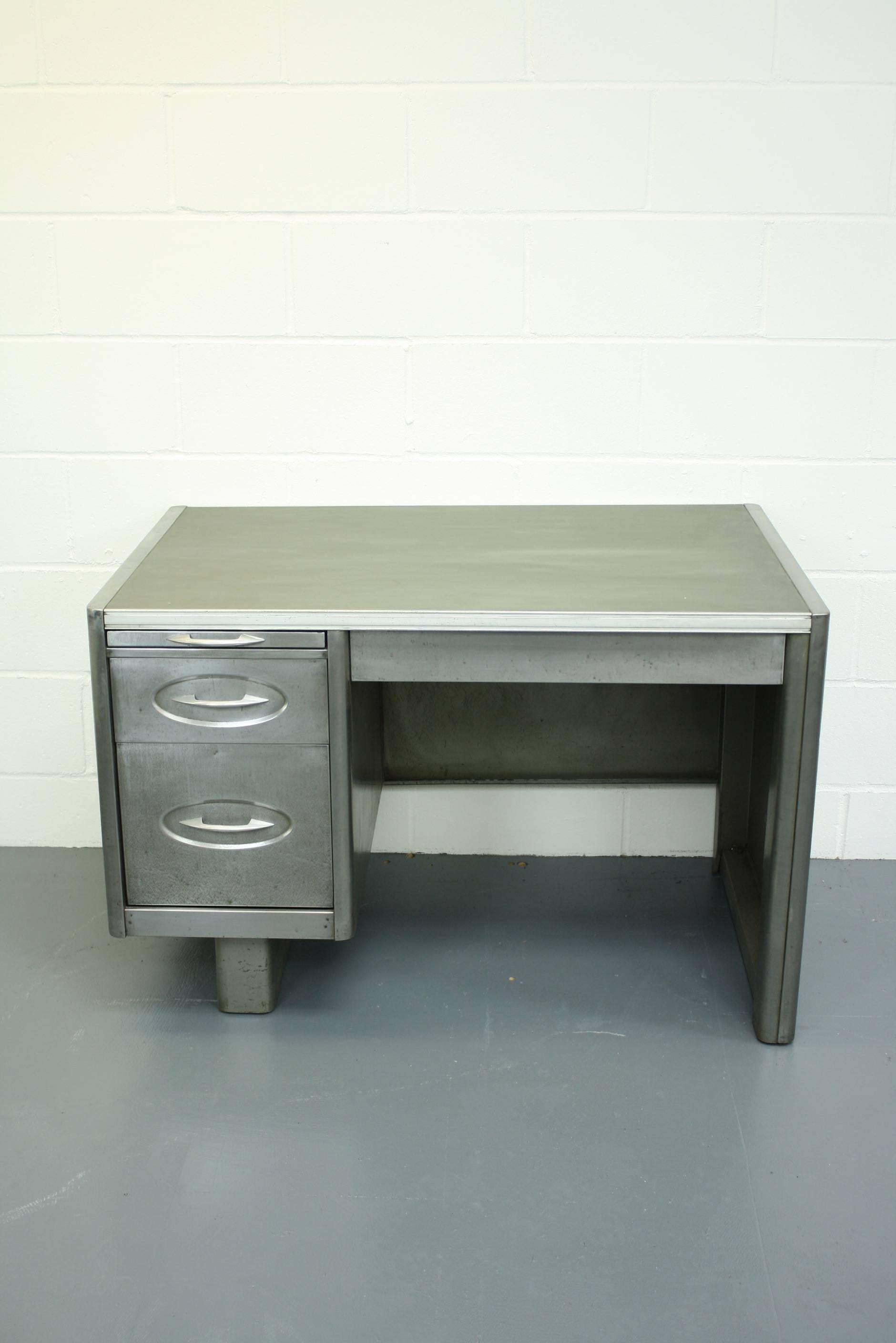 1950s stripped and polished steel desk with drawers and sliding shelf.

In good vintage condition - this piece comes from a working industrial environment and as such, has signs of wear and tear commensurate with age i.e bumps, scuffs etc, all