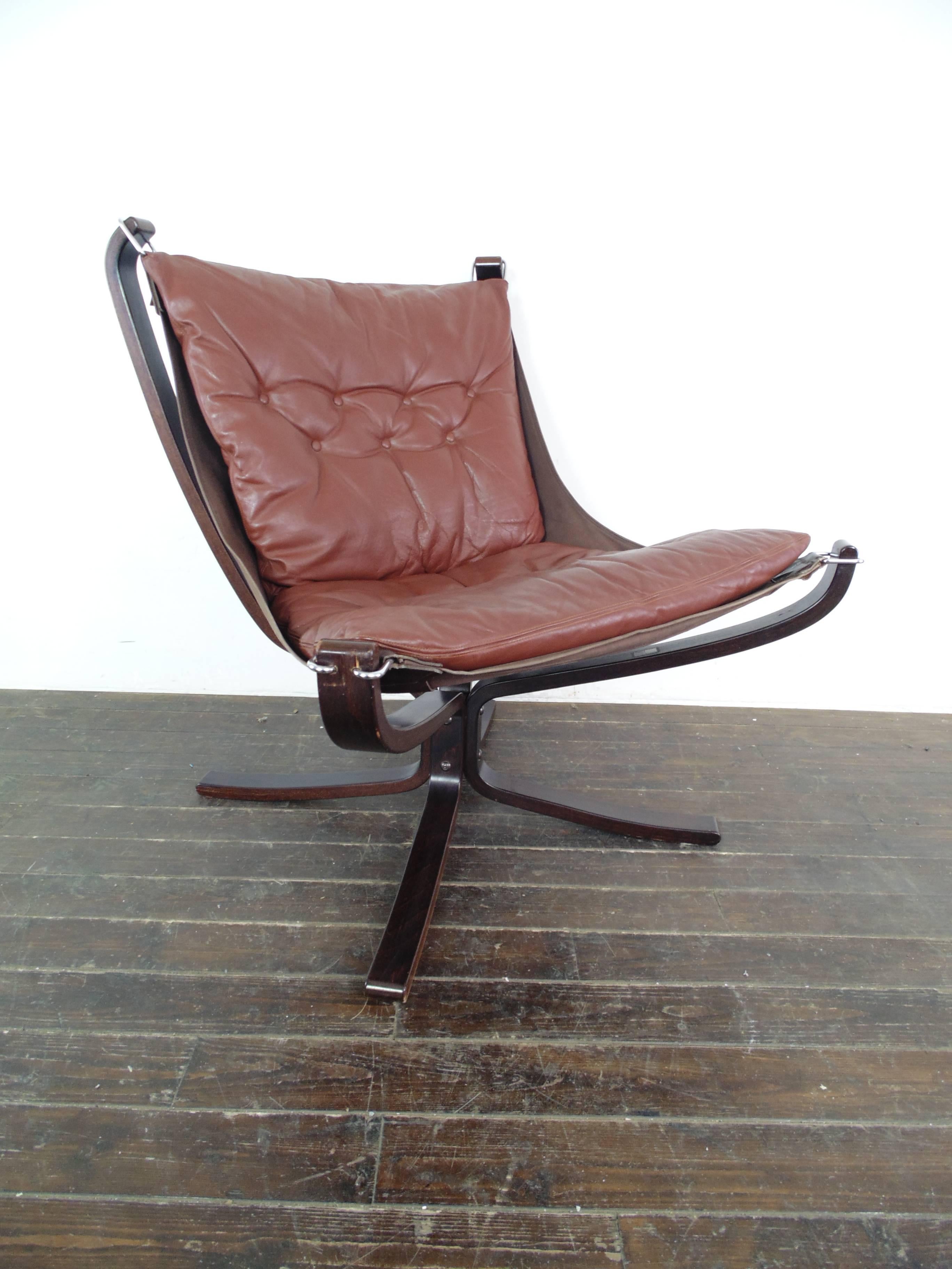 Lovely low back mid brown leather Falcon chair designed by the Norwegian designer, Sigurd Resell, in the 1970s. With rosewood base which is an X shape. 

In good vintage condition. The leather is in good condition for its age with no rips or tears