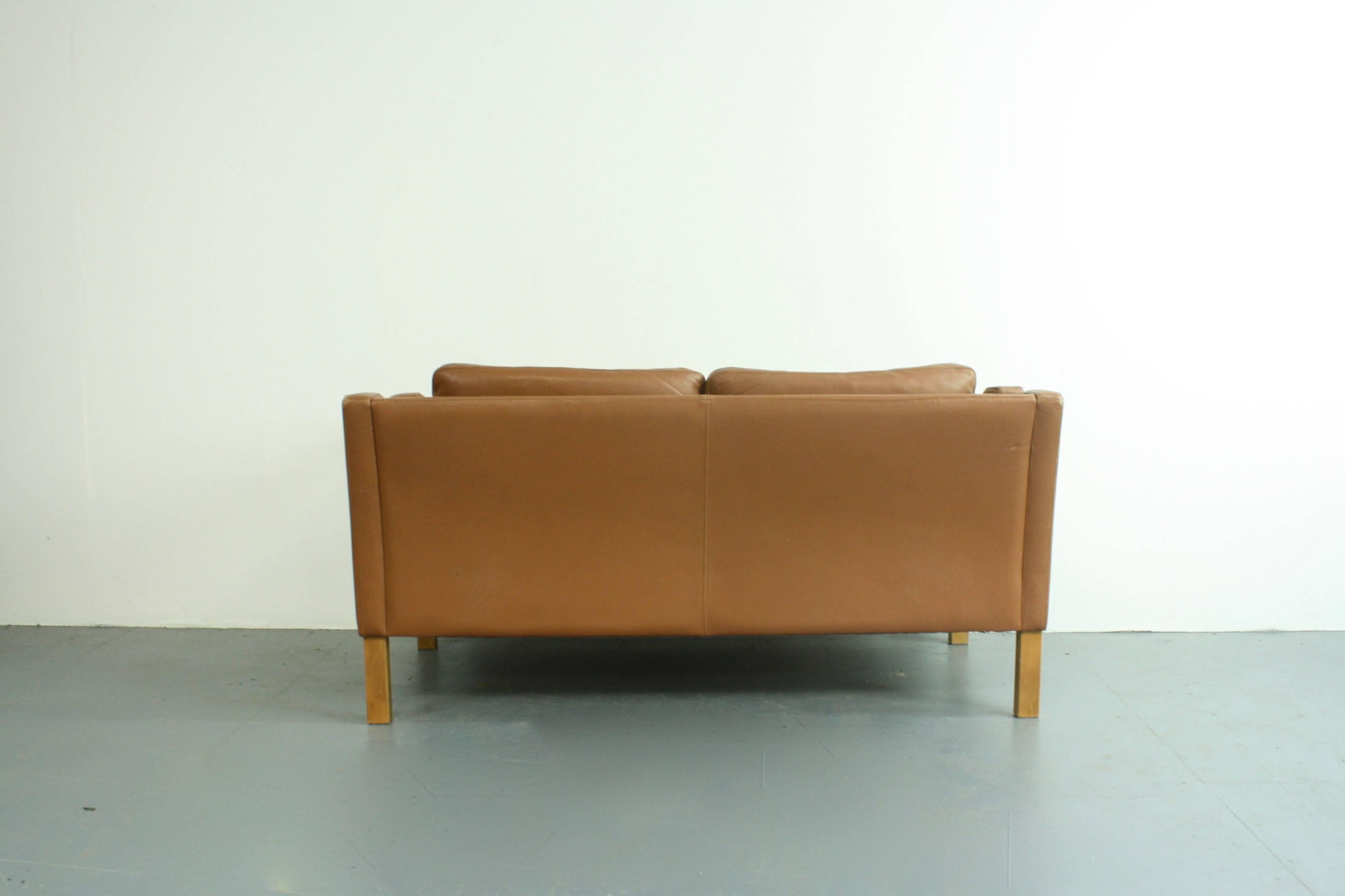 Very nice leather Mogensen style 1970s two-seat sofa. In a lovely midcentury mid brown.

Detachable down-filled seat cushions. Wooden legs.

Approximate dimensions:

Width 138cm 

Height 70cm

Depth 79cm

Seat height 43cm.

In good