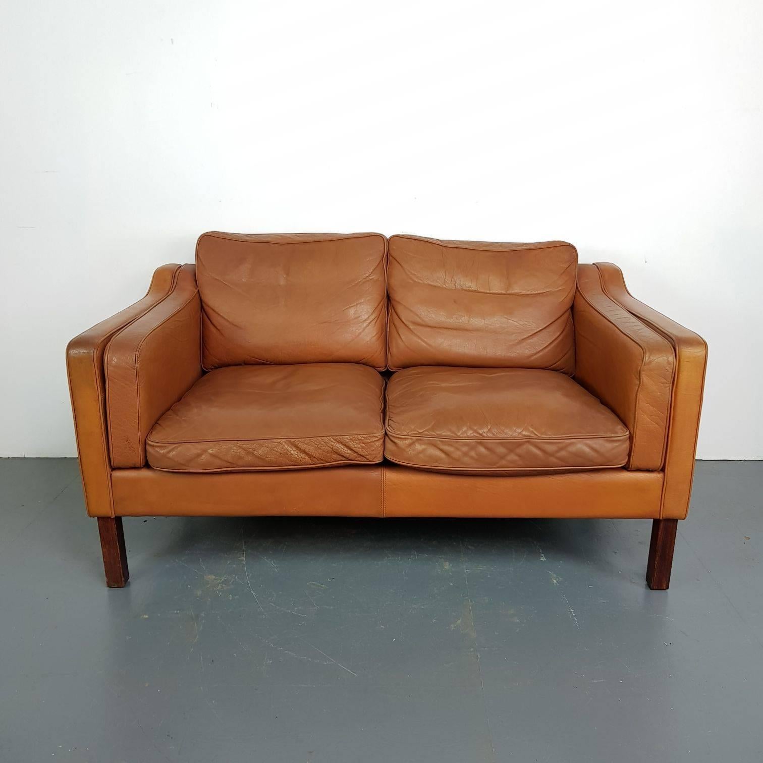 Very nice leather Mogensen style 1970s two-seat sofa. In a lovely midcentury tan brown.

Detachable seat cushions. Wooden legs.

Approximate dimensions:

Width 138cm 

Height 75cm

Depth 80cm

Seat height 44cm.

In good vintage