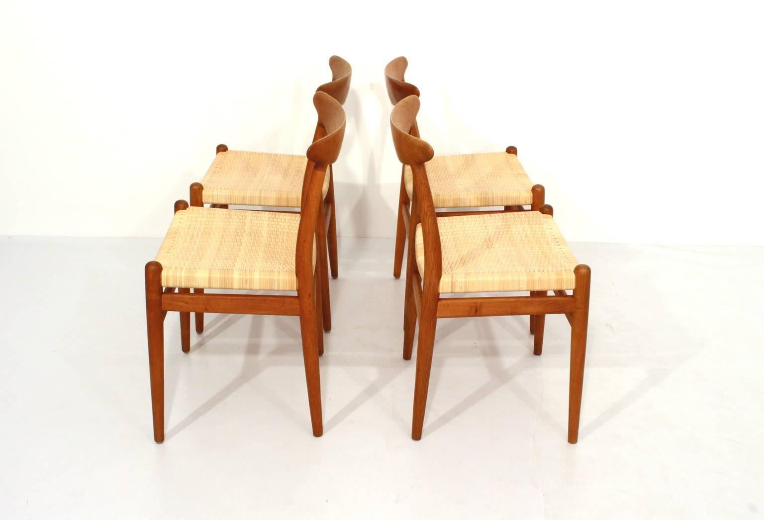 A set of four dining chairs, model W2.
Design Hans J Wegner, 1953. Made by CM Madsen, Denmark.
Solid oak with fine patina, seats with new woven rattan.