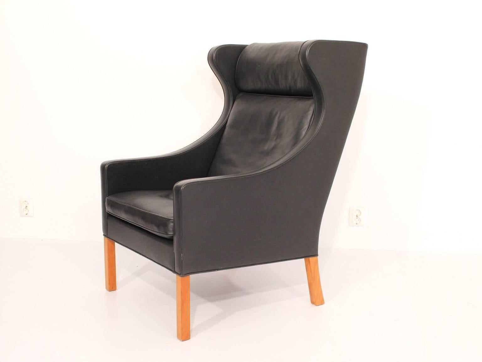 Wingback chair in original black leather.
Design Børge Mogensen, 1963.
Made by Fredericia Stolefabrik, Denmark.

Mogensen's high back wing chair has a sharply defined outline and a softly encompassing interior, which has made it one of his most