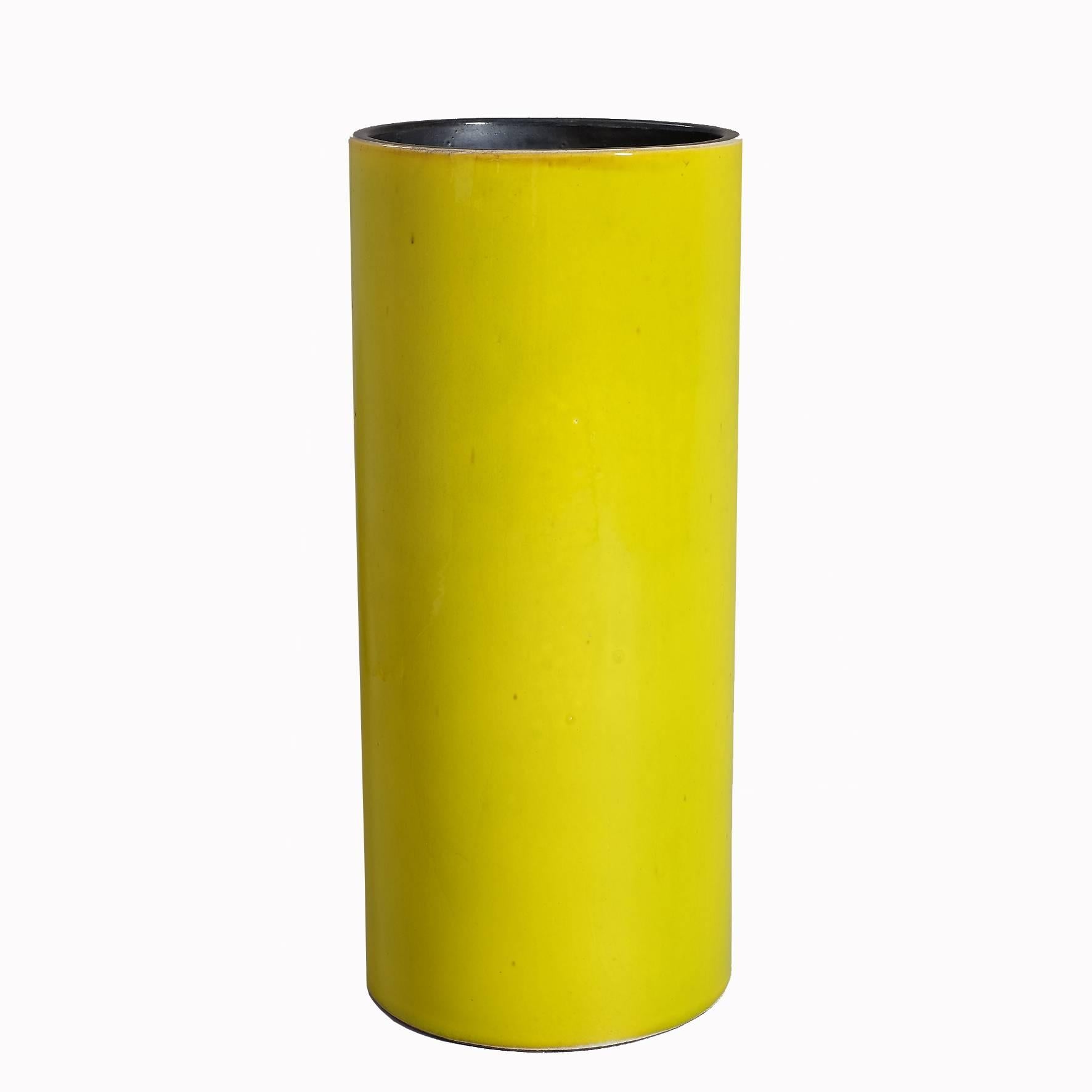 A tall yellow-green glazed ceramic cylindrical vase, with a black covered interior.
Signed underneath 