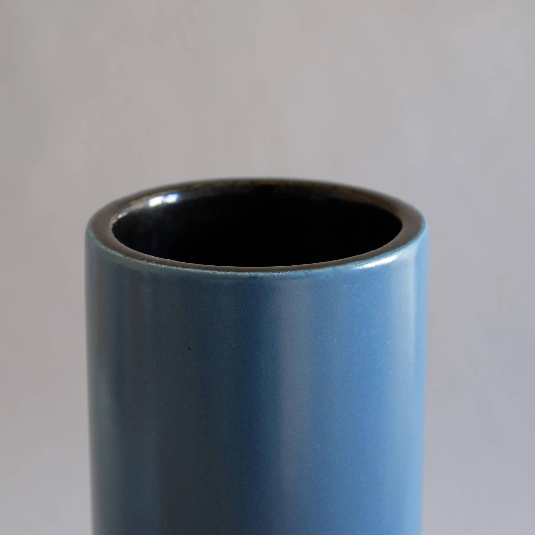 A blue ceramic cylindrical vase, with a black covered interior.
Signed underneath Jouve and artist’s cypher Alpha.