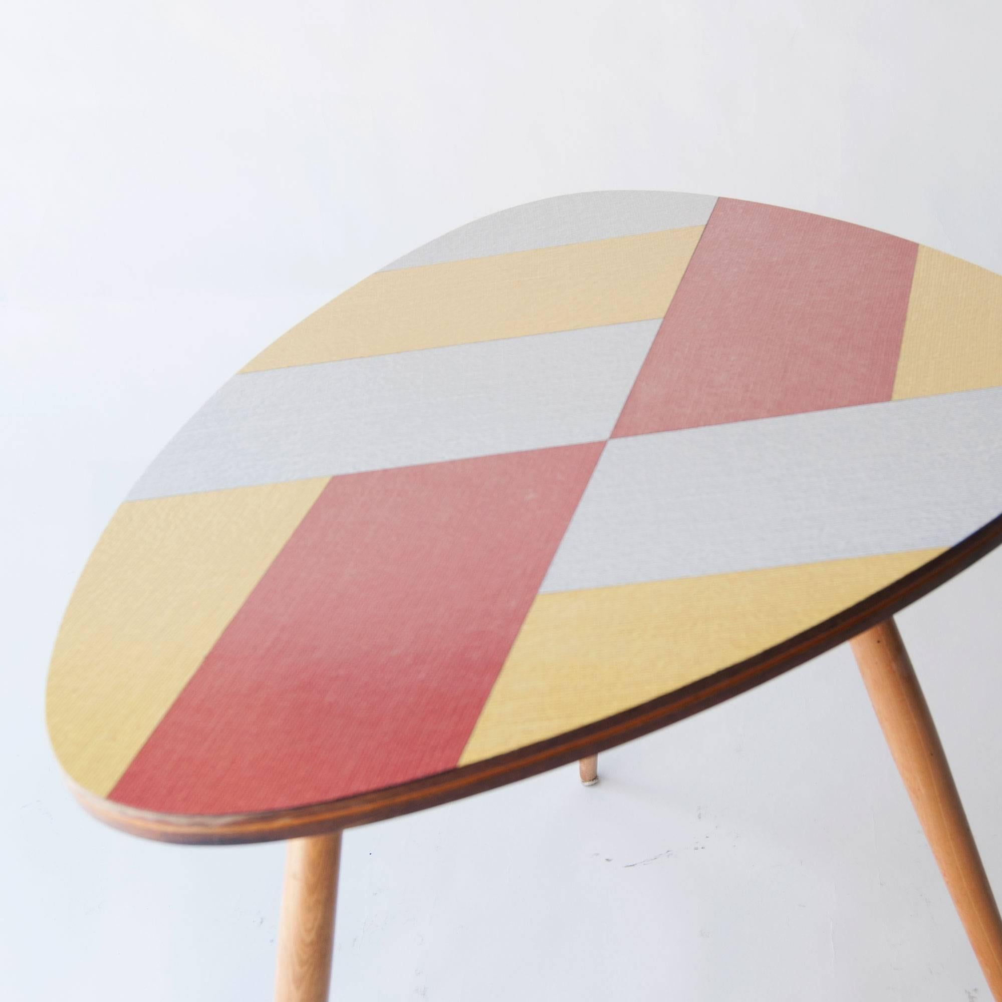 Pair of oak structure tables with conic legs and top made in formica decorated with a geometric design in different colors.