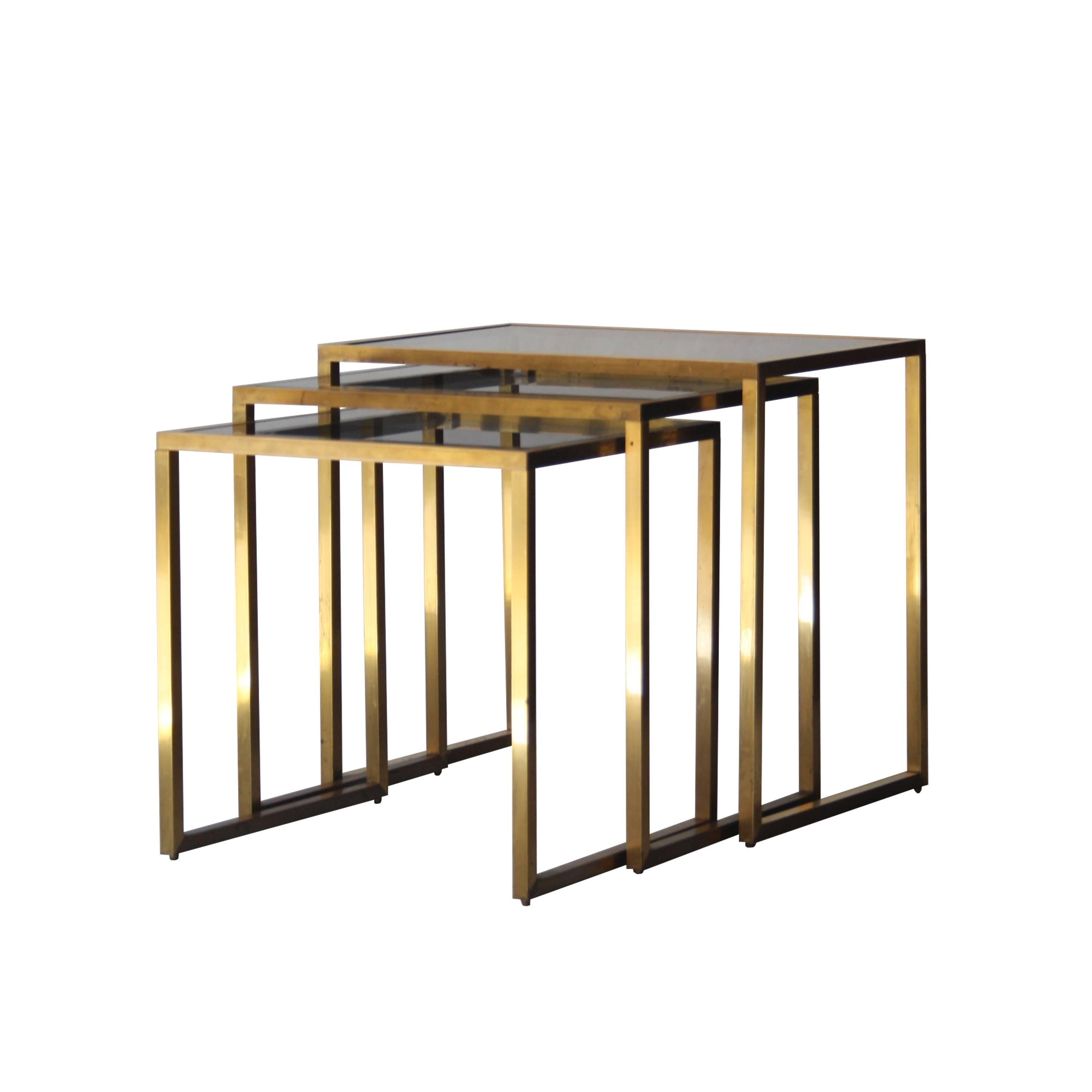 Set of three nest side tables with brass structure and smoked glass tops.