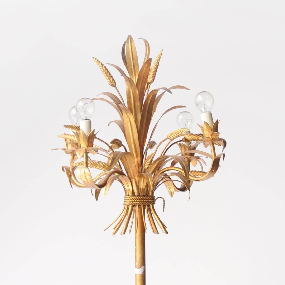 Floor lamp made in metal with a golden patina with vegetal details at the structure and four points of light as a bulb.