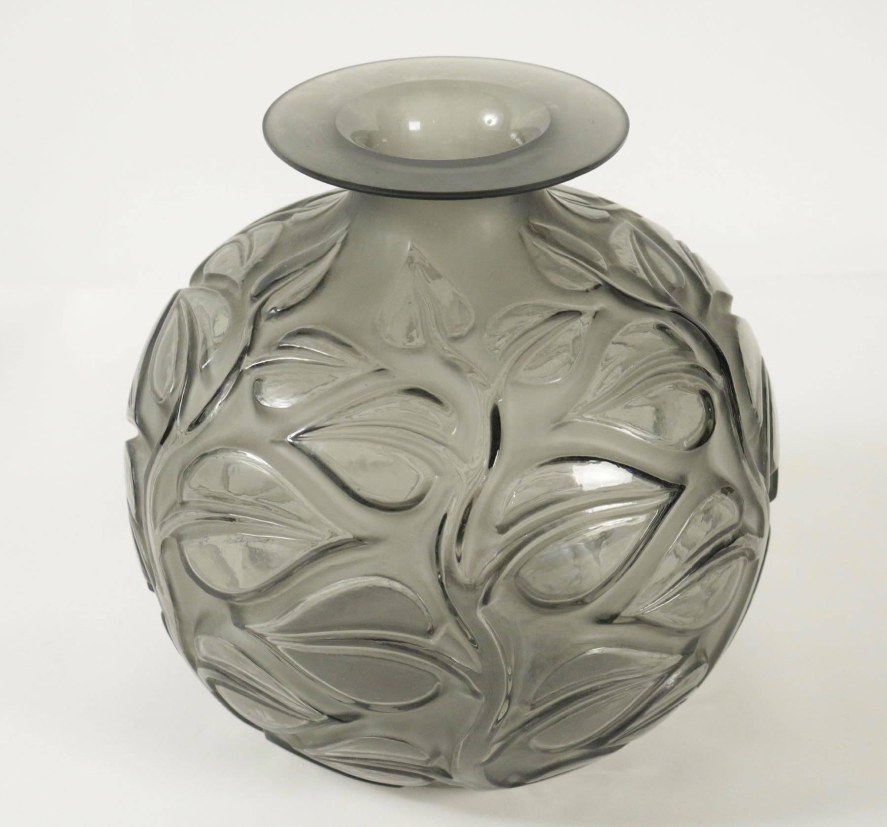 The body covered with large medium relief leaves on stems all in grey glass 26 cm tall.
Frosted glass decorated with large leaves on recessed thick stems under a flat and widening rim.
Sophora, model created in 1926, non repris apre's