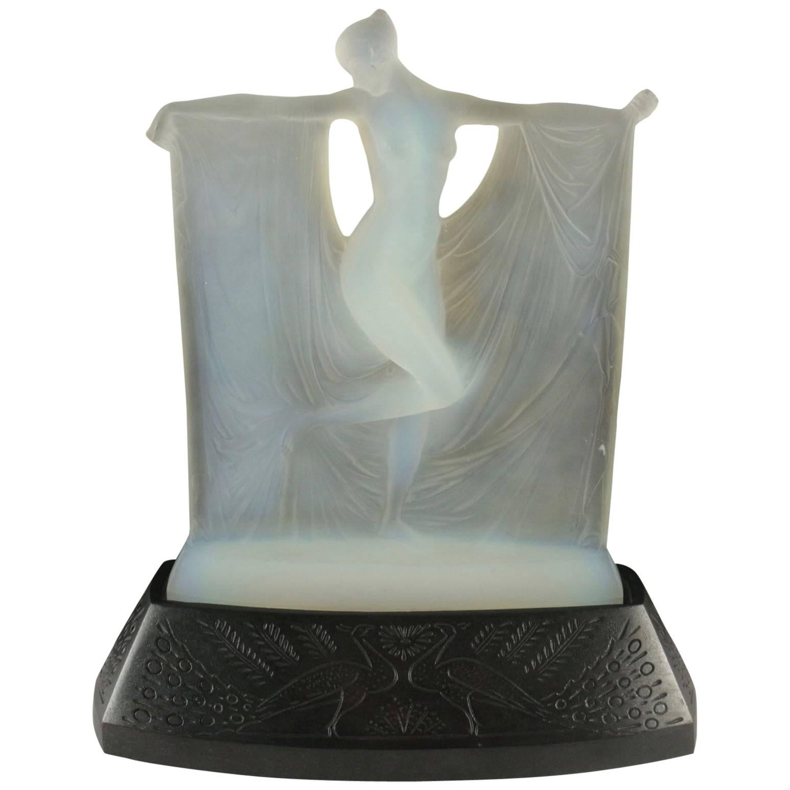 R. Lalique
Opalescent glass statuette, by René Lalique, moulded as a maiden amidst drapery held by her outstretched arms, signature to rear of the figure above base, moulded in relief, R.Lalique.
A fine blue/white opalescent glass statuette, by