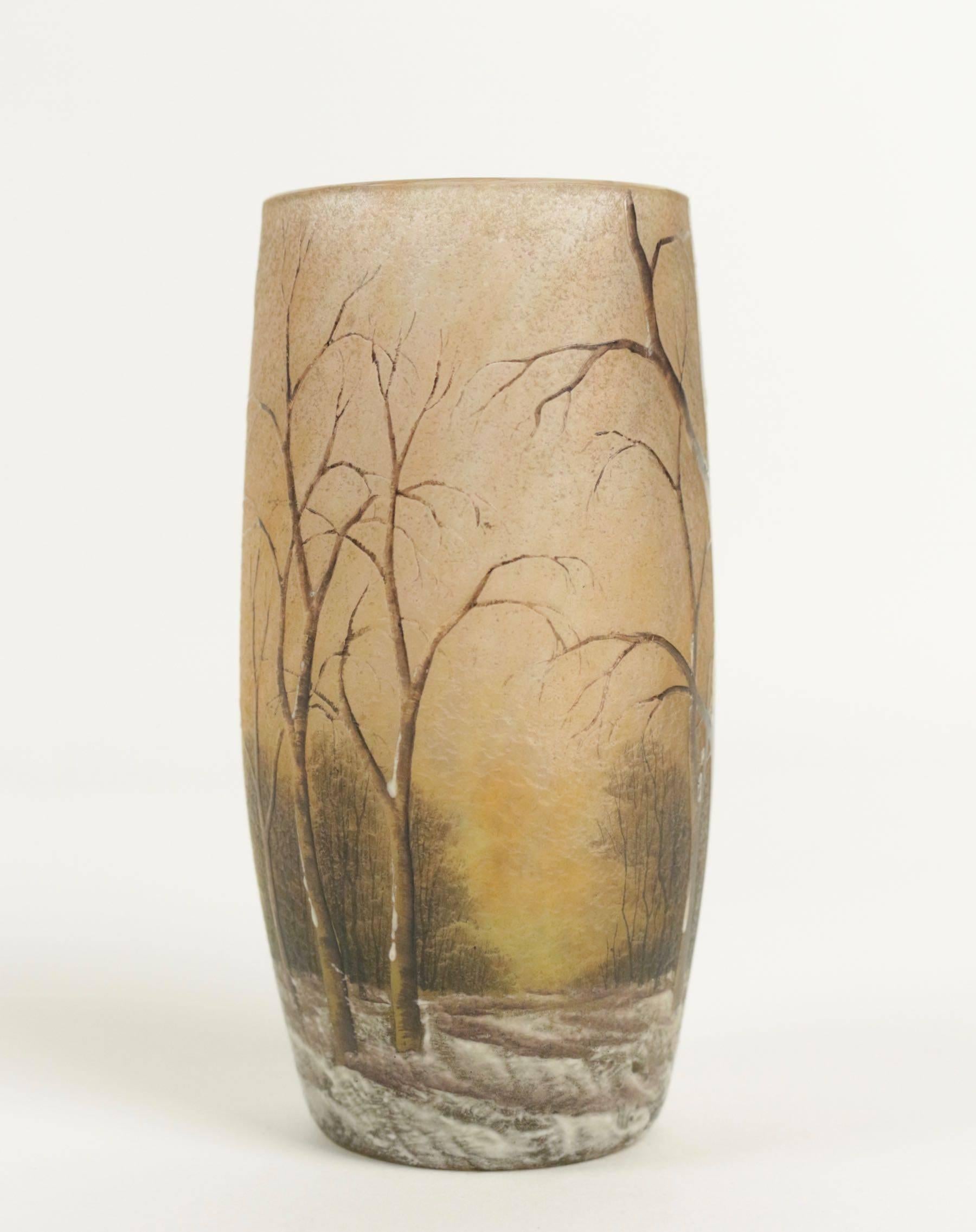 An enameled glass 'winter landscape' vase.
Daum cameo and enameled winter scene vase.
Daum vase has decoration of barren trees rising from snow covered ground against a mottled orange and yellow background. Trees are nicely enameled in shades of