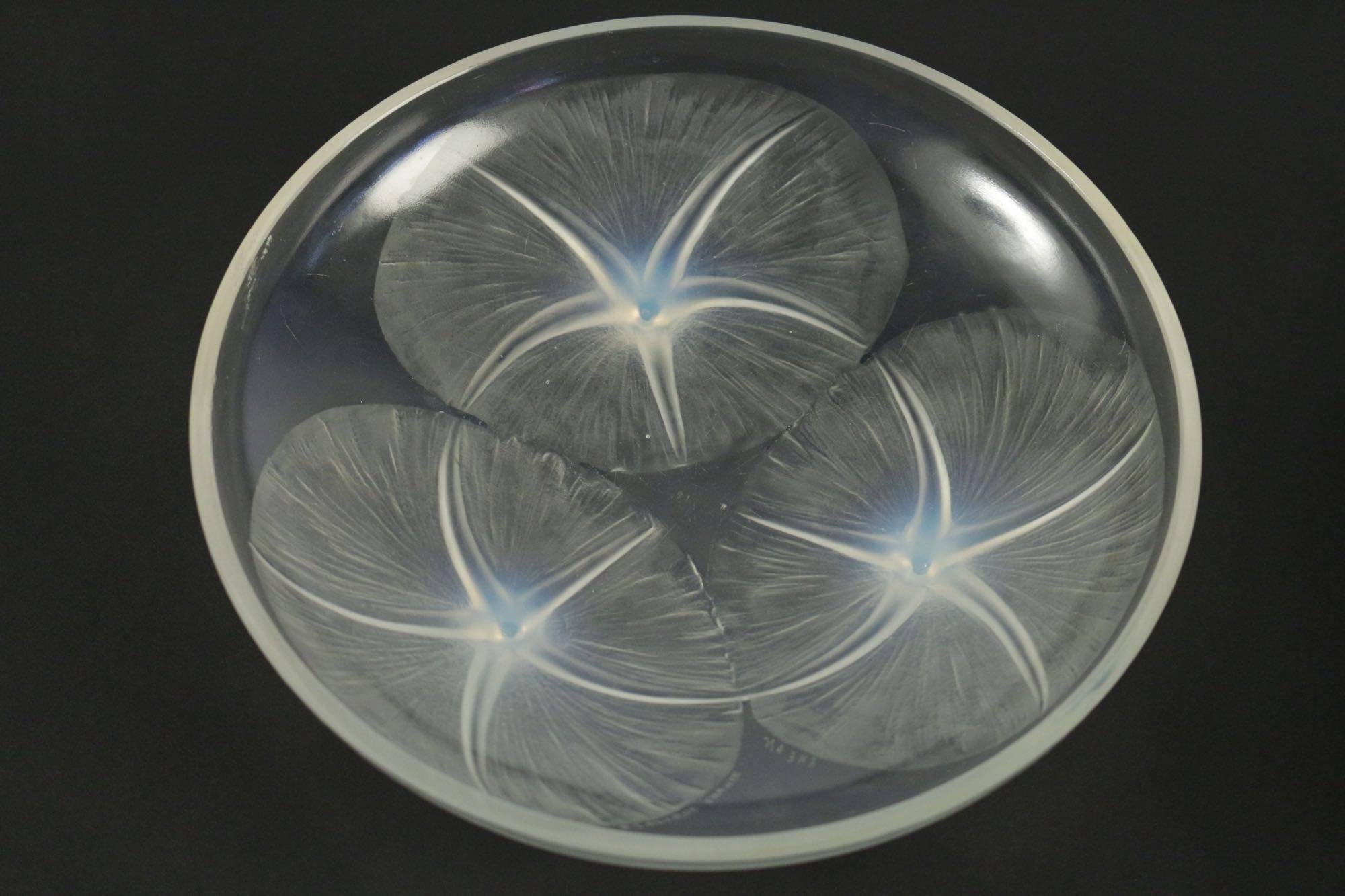 René Lalique (1860-1945)
Volubilis, 1921 Bowl molded, pressed opalescent glass.
Opalescent glass with three large flower heads whose stems are the feet of the cup;
slightly elevated on three feet that are the stems of the flowers.
Signed R.