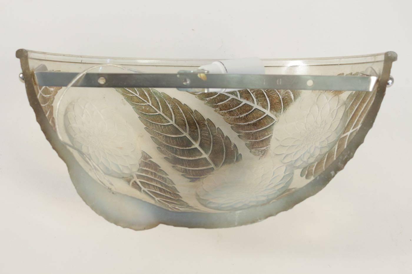 A pair of 30.5 cm wide opalescent glass half bowl form floral decorated
leaf and flower head design on opalescent and brown and green patinated glass R. Lalique wall sconces.
Model created in 1921
Modèle reproduit dans le catalogue raisonné de