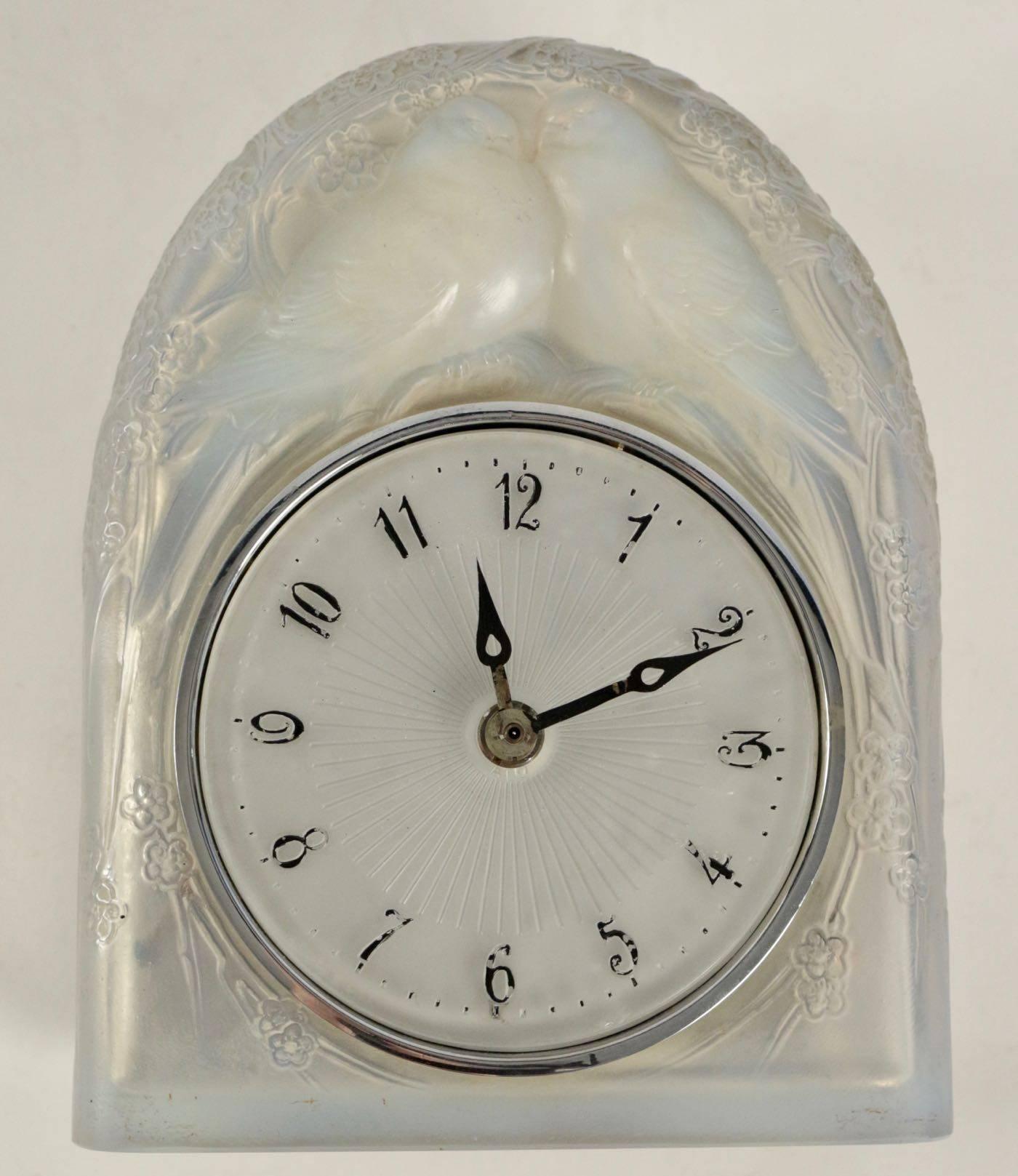Deux colombes, a moulded-pressed opalescent and satiny glass mile-stone clock 

Glass dial with black enemailed number
 Two perched birds on branches and foliage motif under a dome shaped.
Signed R.Lalique, France.
Model created in