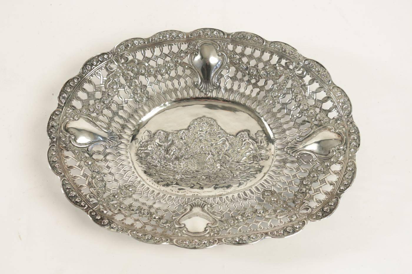 19th century European sterling silver pierced dish with a cherub motif in the centre. Immaculate detailing.
Five cherub and garlands of flowers
Cherub scene playing entwined in garlands of flowers
Measures: 27 cm X 33 cm X 5 cm.