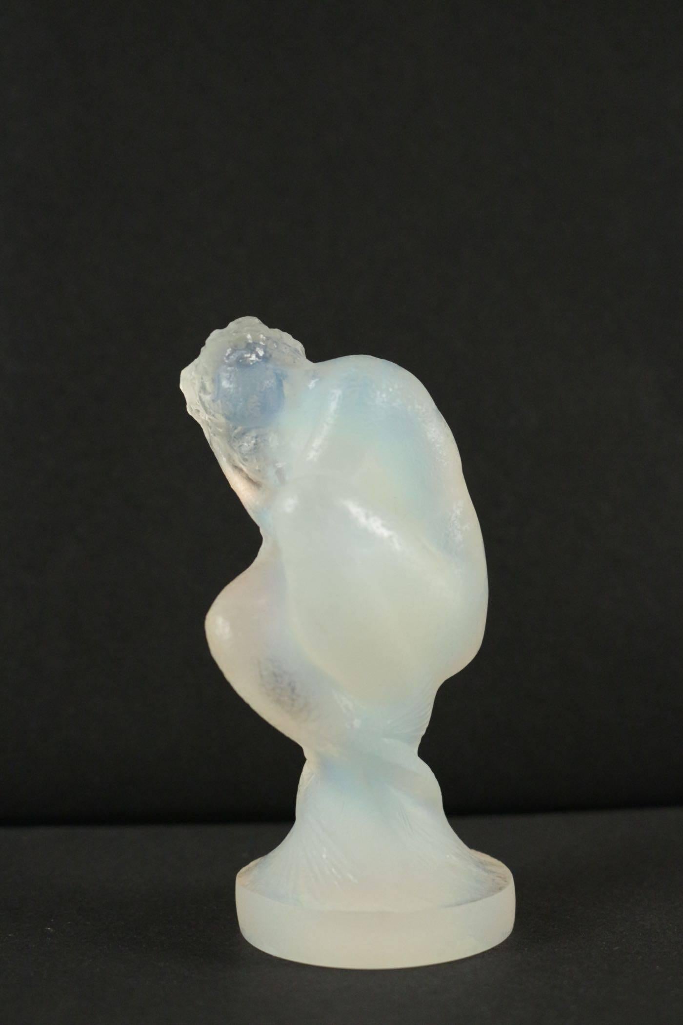 Opalescent glass crouching mythical mermaid type female figure holding a shell to one ear
Small statuette, model created in 1920 opalescent, moulded-pressed glass, model “Sirène”. Signed “R.Lalique France”. Model created in 1920. Measure: H 4 in