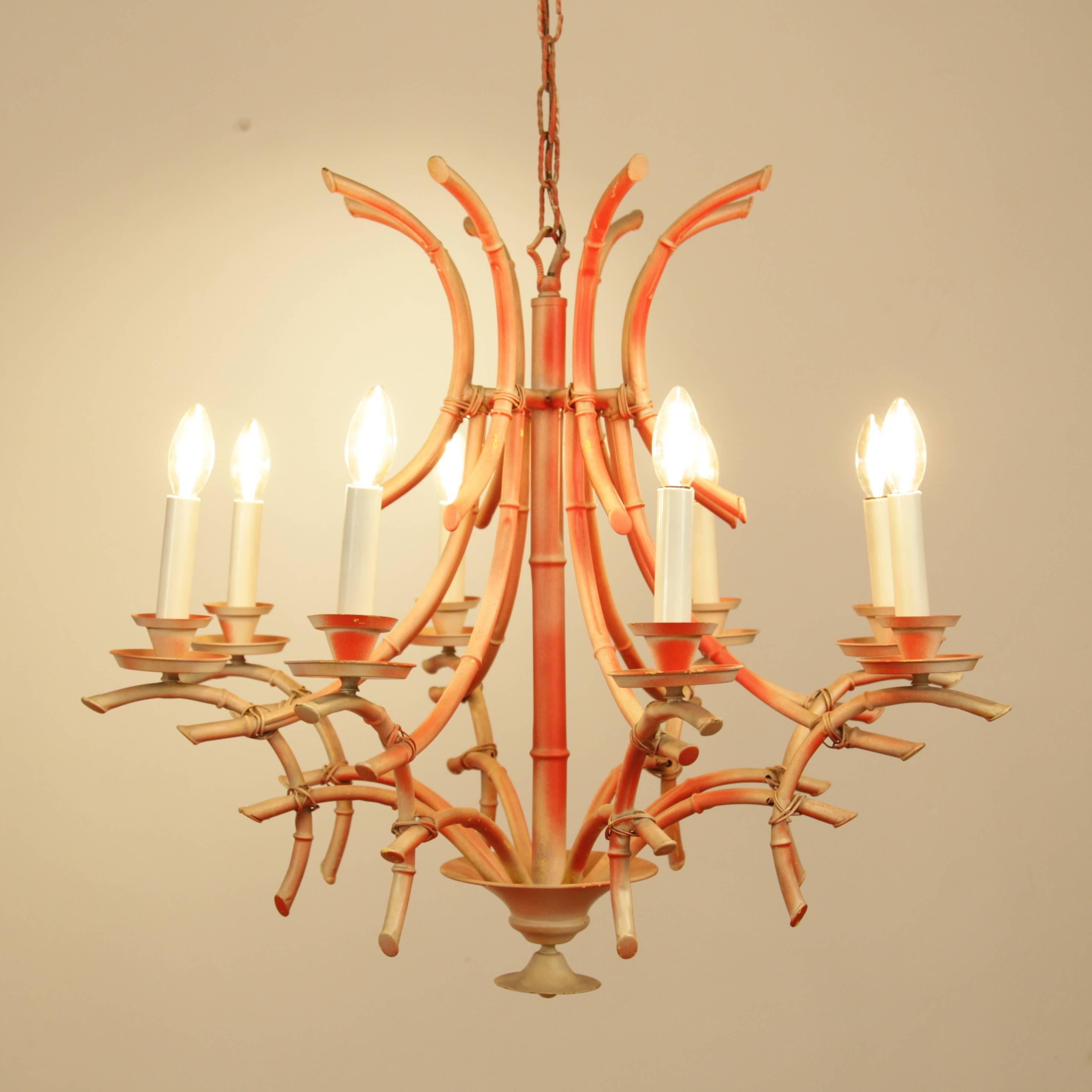 Italian coral painted bamboo chandelier. The chandelier has eight arms and lights and a Classic Chinese Chippendale form.
