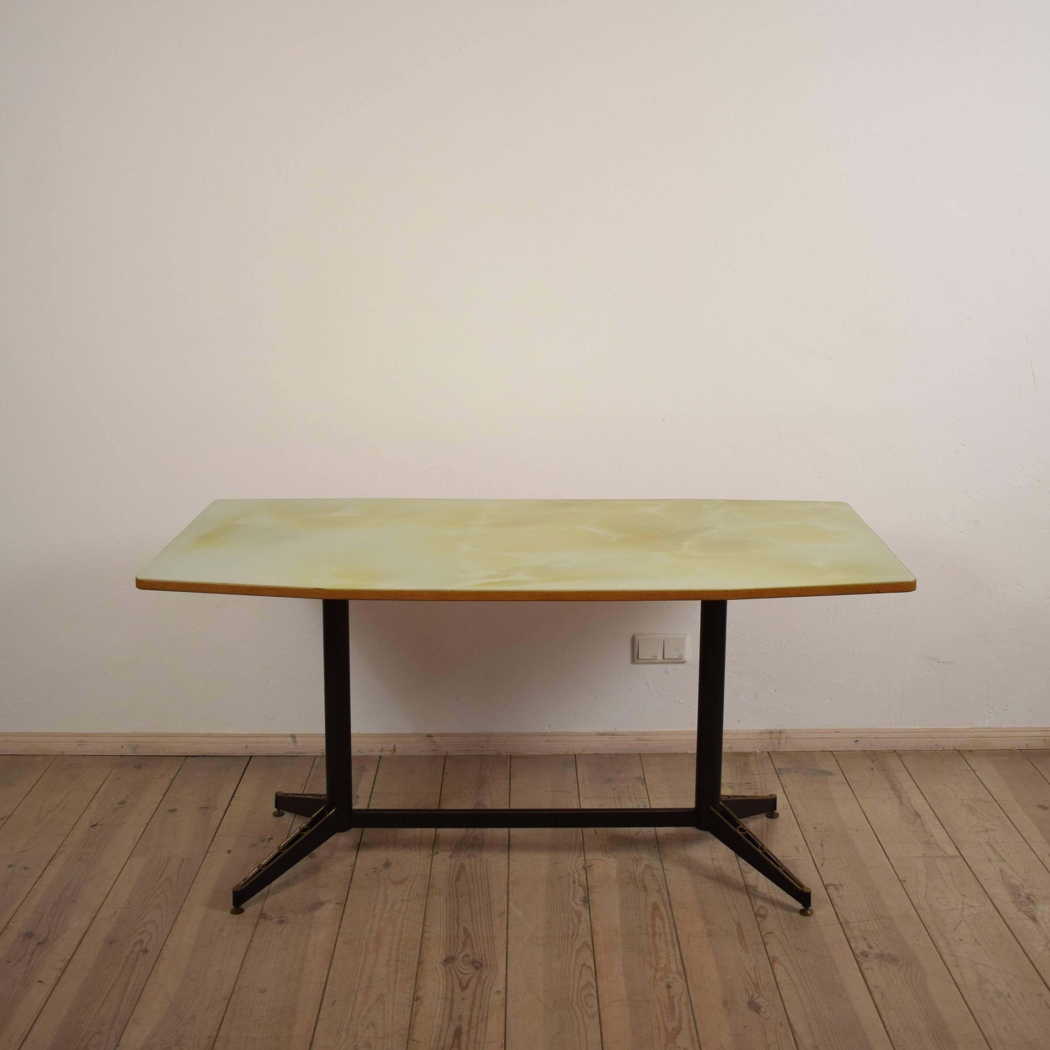 This elegant glass top dining table shows the great design of the 1950s in Italy. The glass top is painted on the back and locks like light green marble. The metal base is a clean design with some great brass features on the end of the legs. This