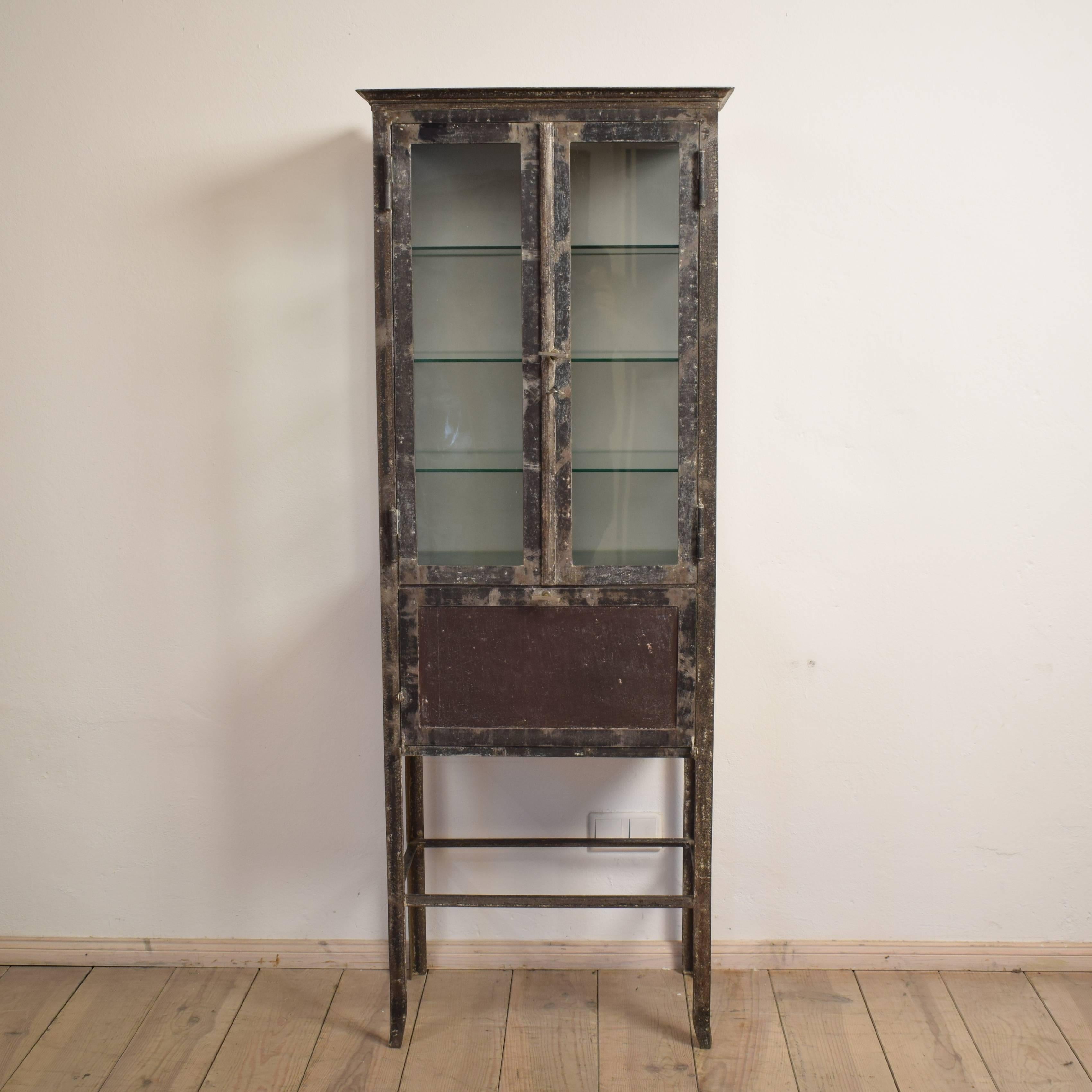 This Industrial Bauhaus style display cabinet was made circa 1930. The top part features glass and the lower part is closed and features a flap door.