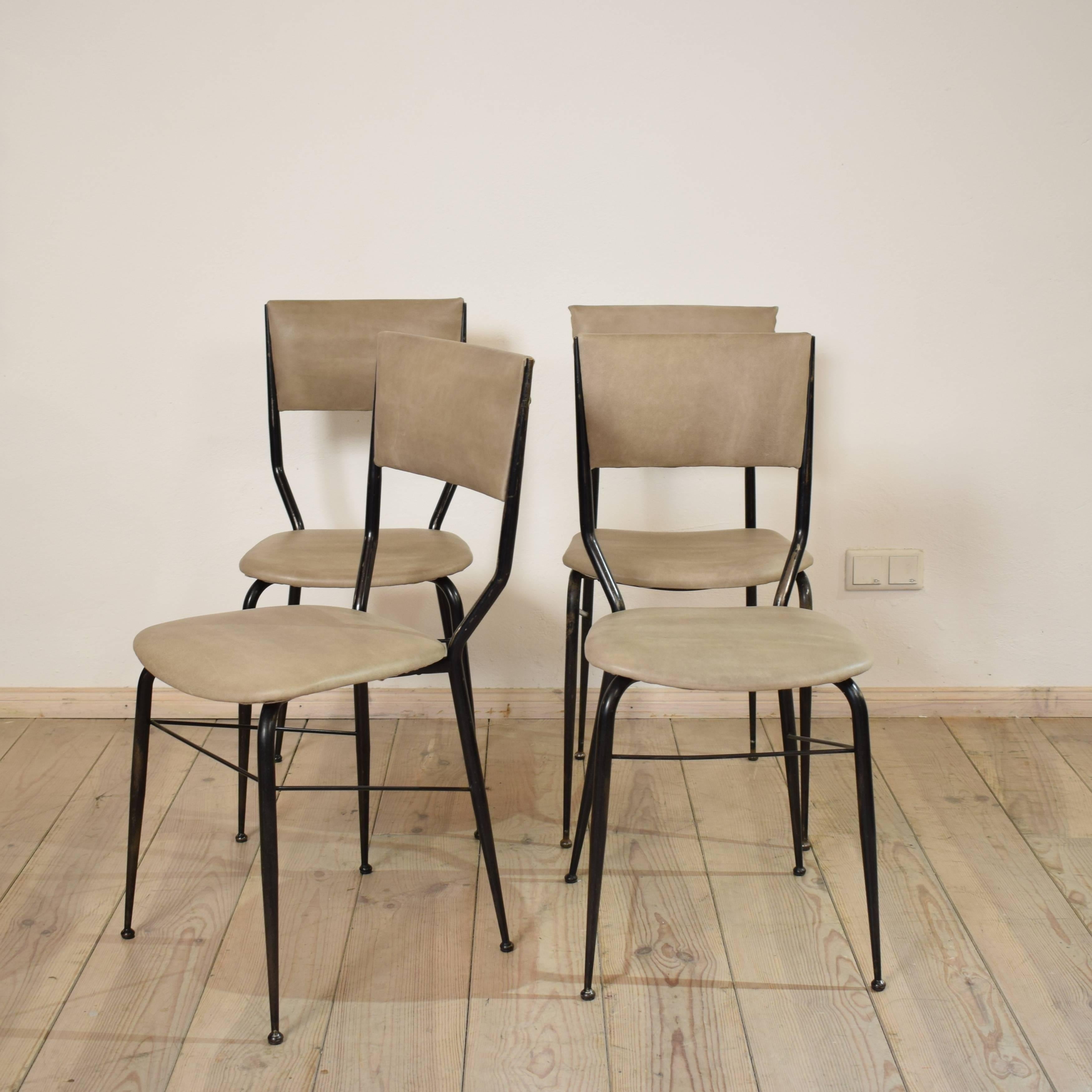 This set of four chairs from the 1950s was designed and manufactured in Italy. The chairs consist of an elegant metal frame and a padded seat and backrest. Three of the chairs are identical. One has a different backrest. The chairs have been newly