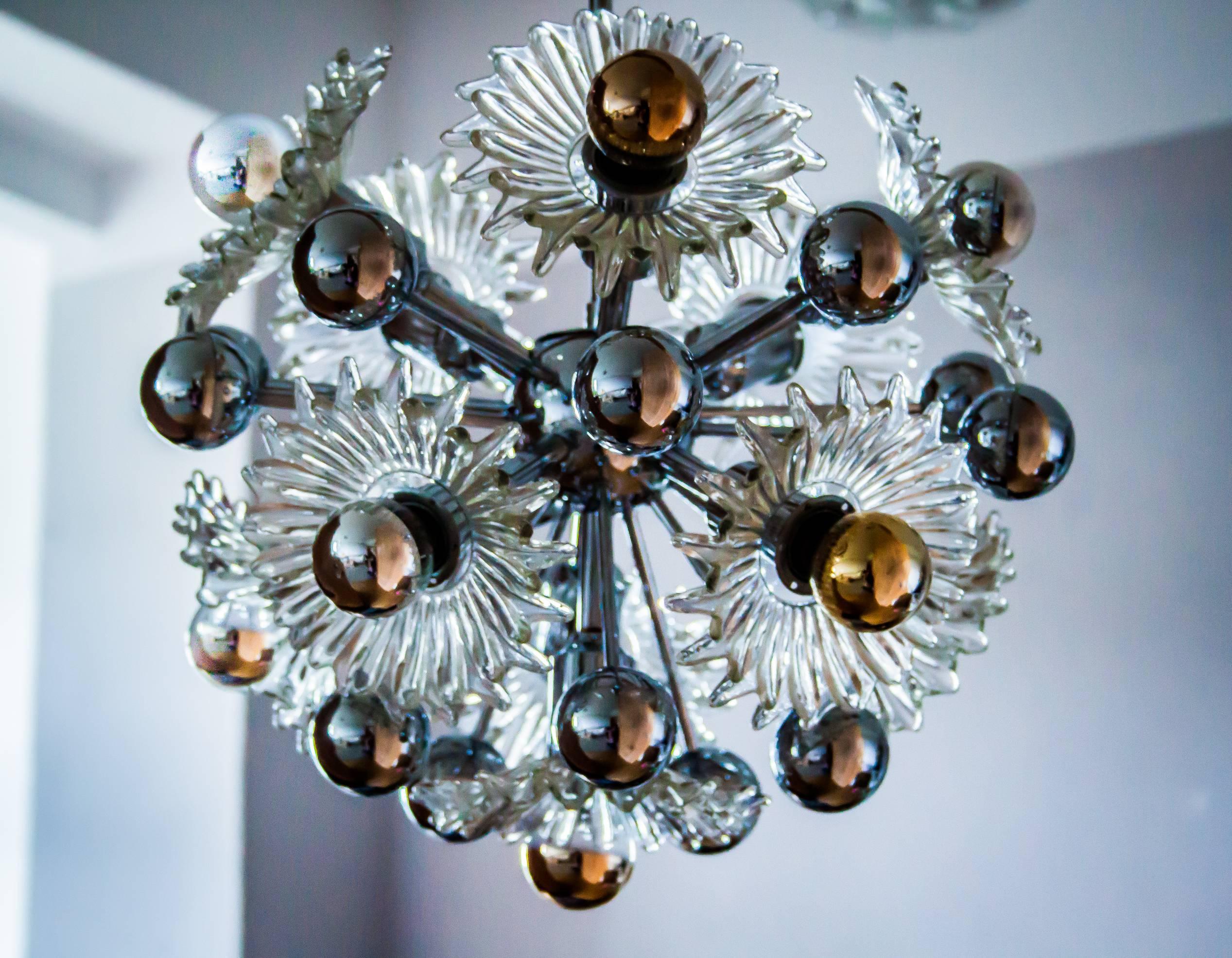 The ceiling pendant includes 11 fine crystal handmade glass flowers witch create a nice light effect at any room. 
The fixture is in near mint condition, has nearly no signs of use. See photos.
It has 15 chrome globes and 11 E 14 sockets for