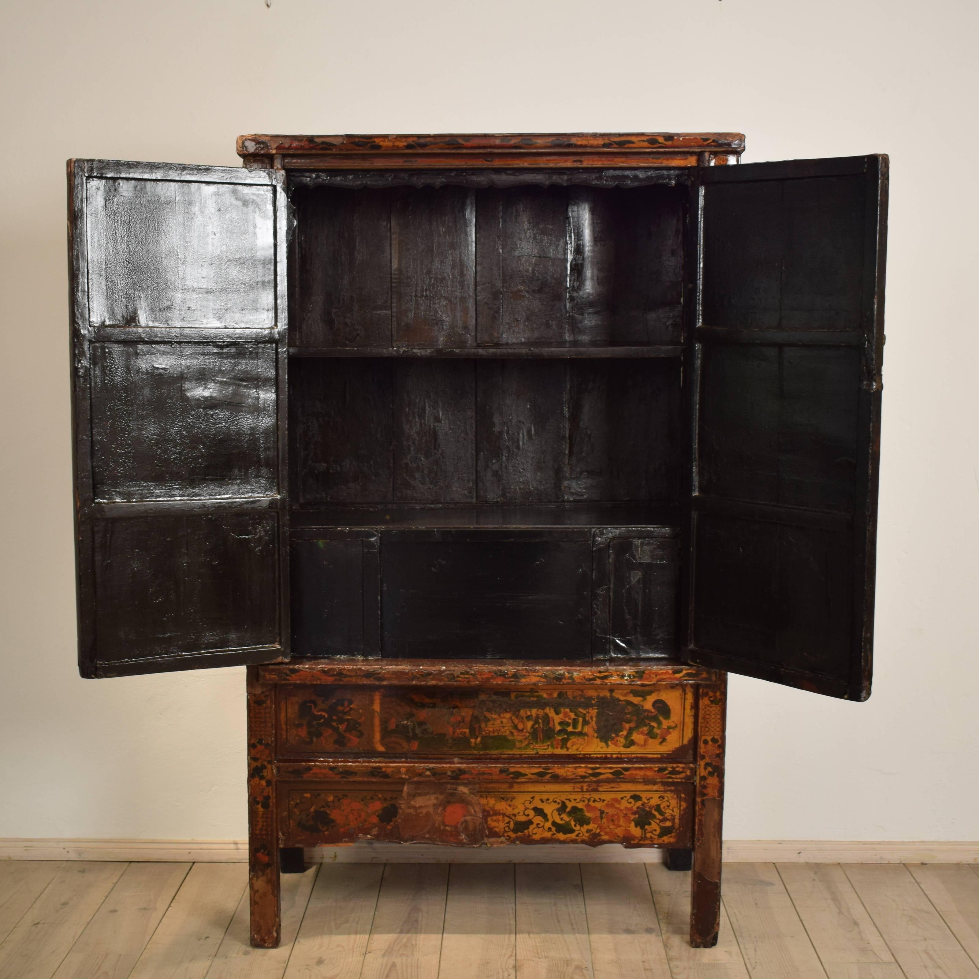 This 1890s Chinese cabinet is made of wood with polychrome designs and a lacquered finish. The front of the cabinets shows a Chinese family tree. The sides are in black lacquer. and decorative brass hardware. The interior is painted black with a