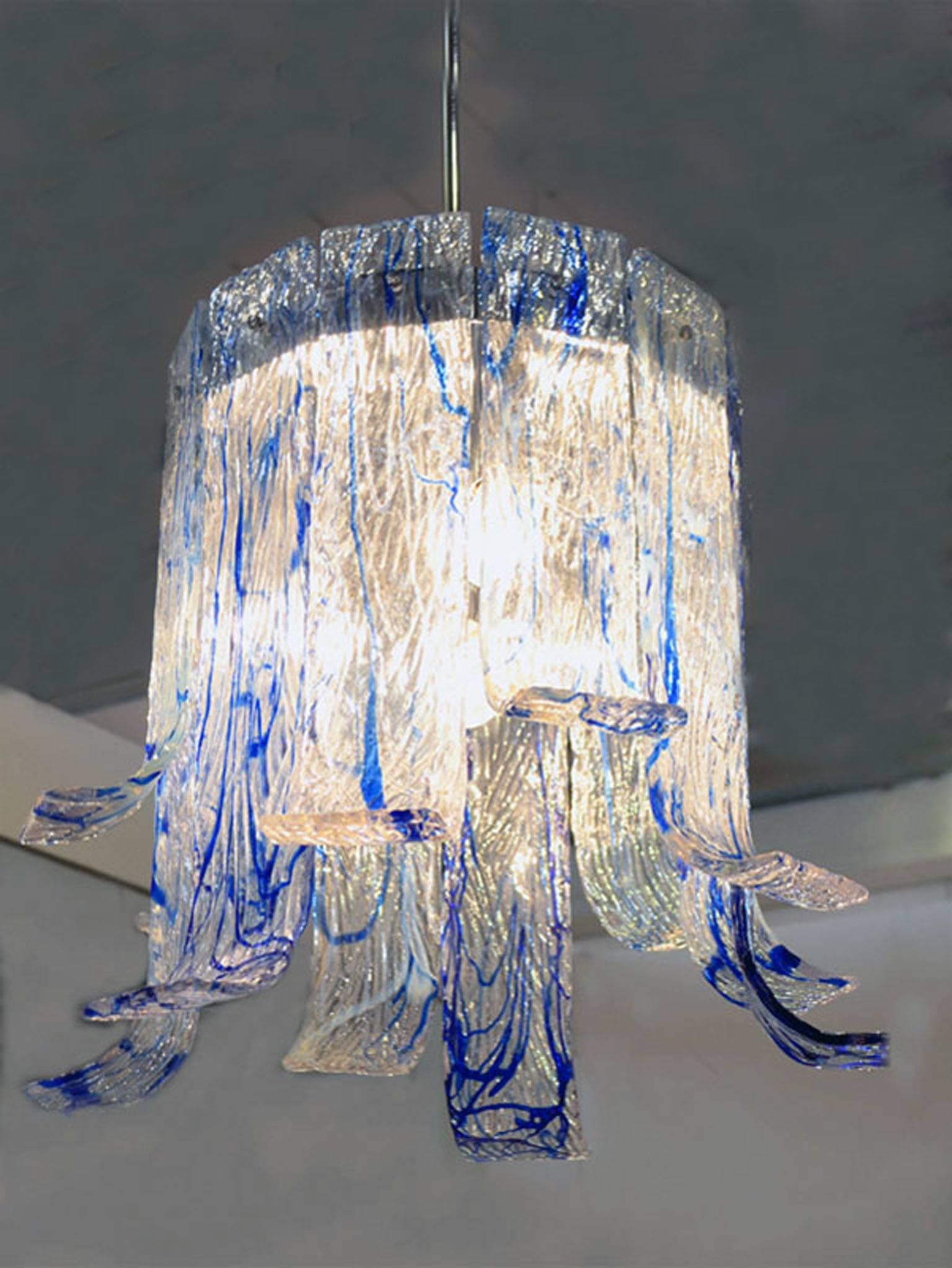 Chandelier produced by Mazzega Murano, 1970s.
Brass structure with glass plates of big and thick in different measures, curved on the bottom.
Transparent glass with hot application of blue glass filament.