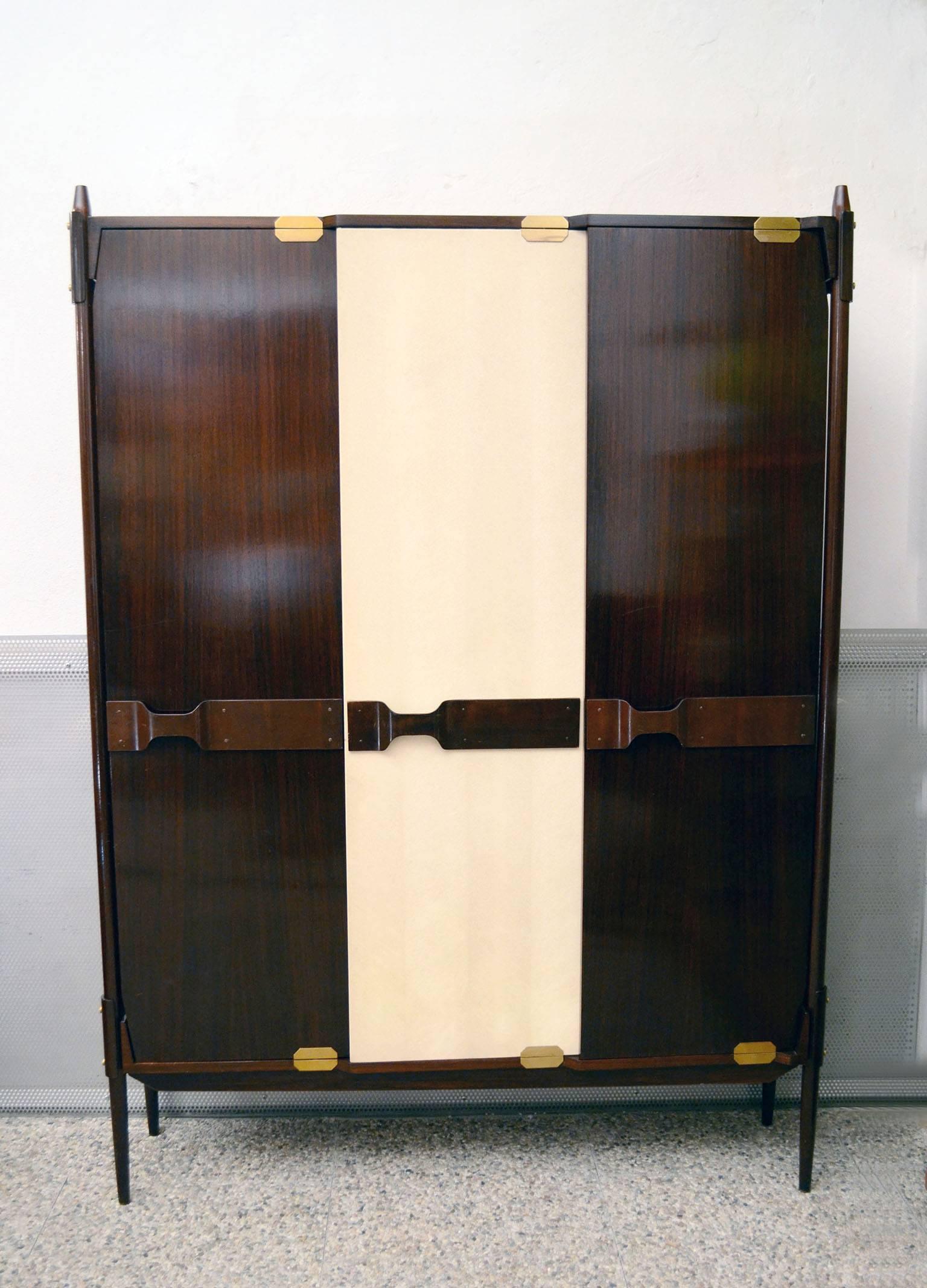 Wardrobe of Italian, 1950s production, attributed to Ico Parisi.
Uprights in solid rosewood, internal finishing and central door covered in vipla.
Handles in curved wood, clothes hangers and details in brass.
