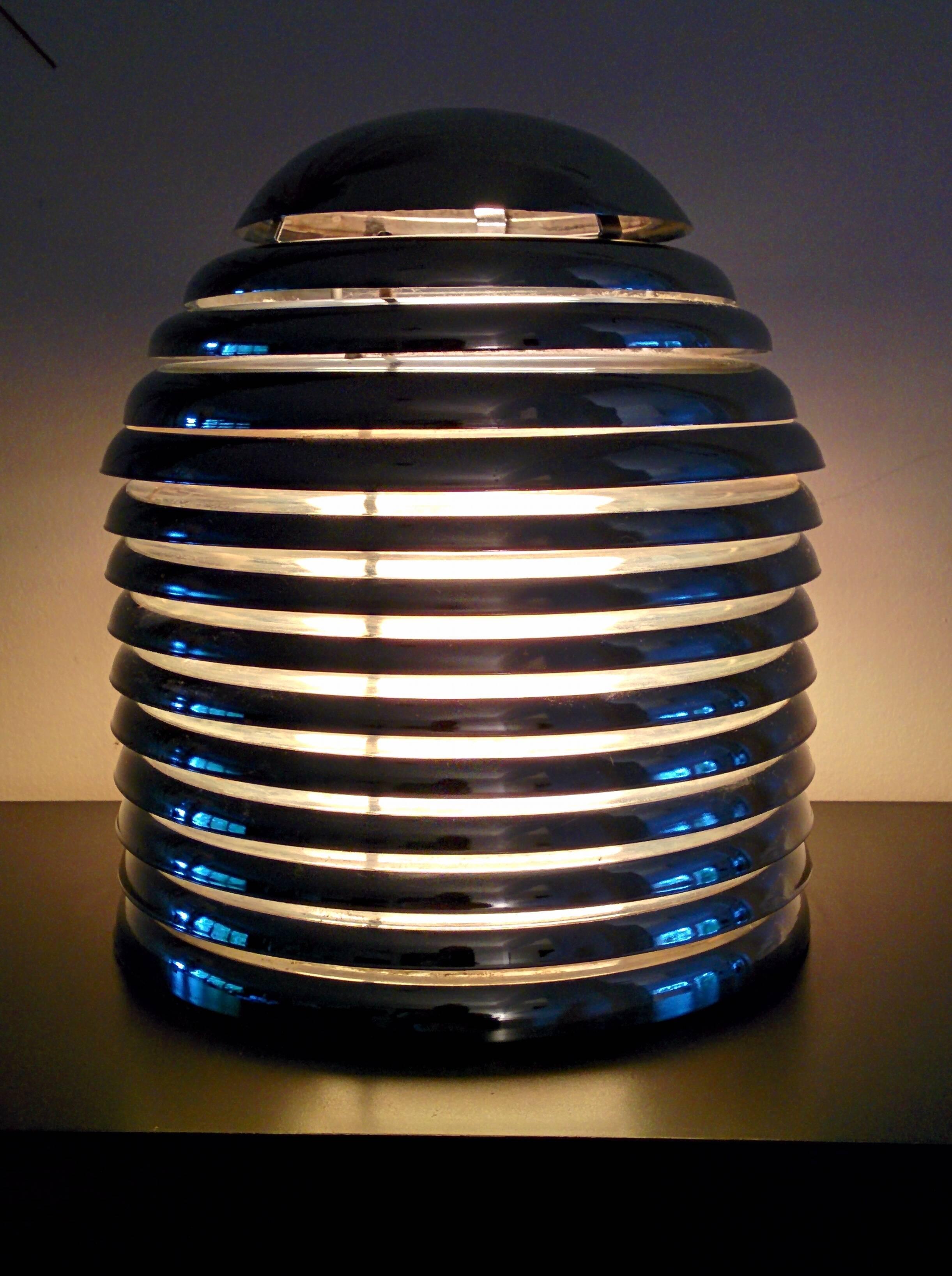Louvered table lamp with convex chrome disk. 

Removable top permit access to lightbulb. 

Original 1970s North American wiring with on or off rotating switch on cord. 

13 inches high by 11 inches wide.

