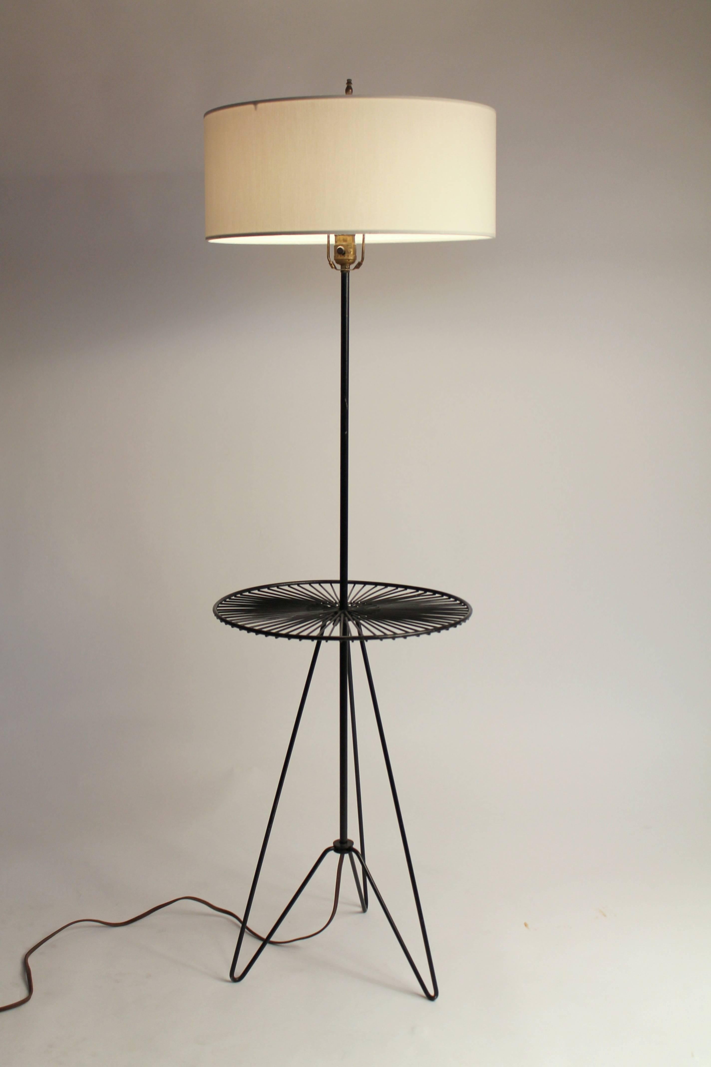This minimalist 1950s floor lamp design is quite elegant and practical with its small table welded on the stem. 

Enameled iron wire.

Well made, superb assembly, extremely sturdy.

Measures: 55 inches to finial, table is 16 inches