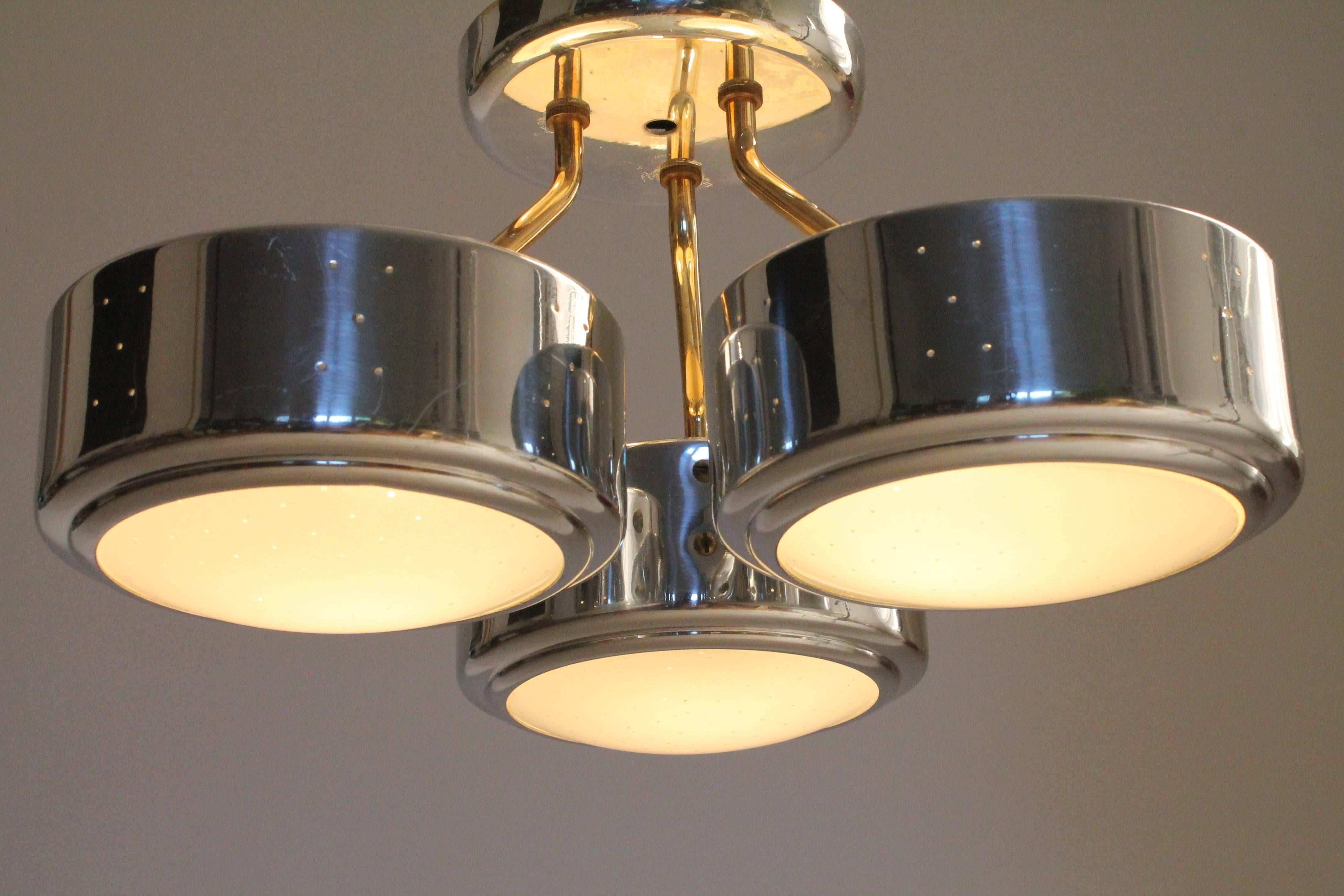 This flush mount is quite unique as they were usually produced in brass-plated version. This one, the gently pierced shade and the canopy are polished aluminium, giving them the appearance of a shiny chrome finish.

The three arms are made of