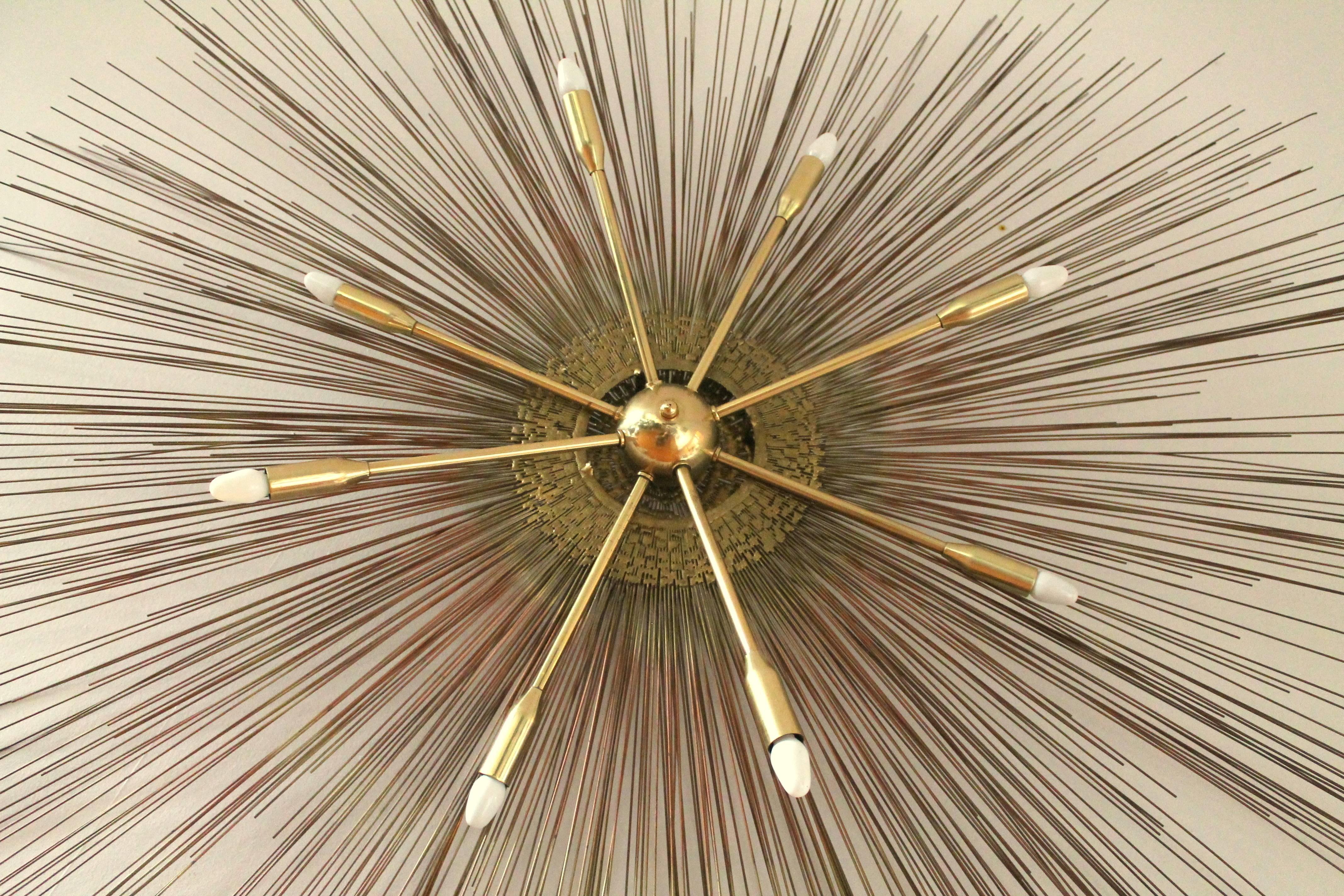 Two-tier wall art combined with an eight arm brass Sputnik measuring 5 foot wide  . 

Steel  rods  with brass welding and accent . 

8  E12 candelabra size socket . 

When lighted, the shadow projected on the wall make the rods appear close to 7