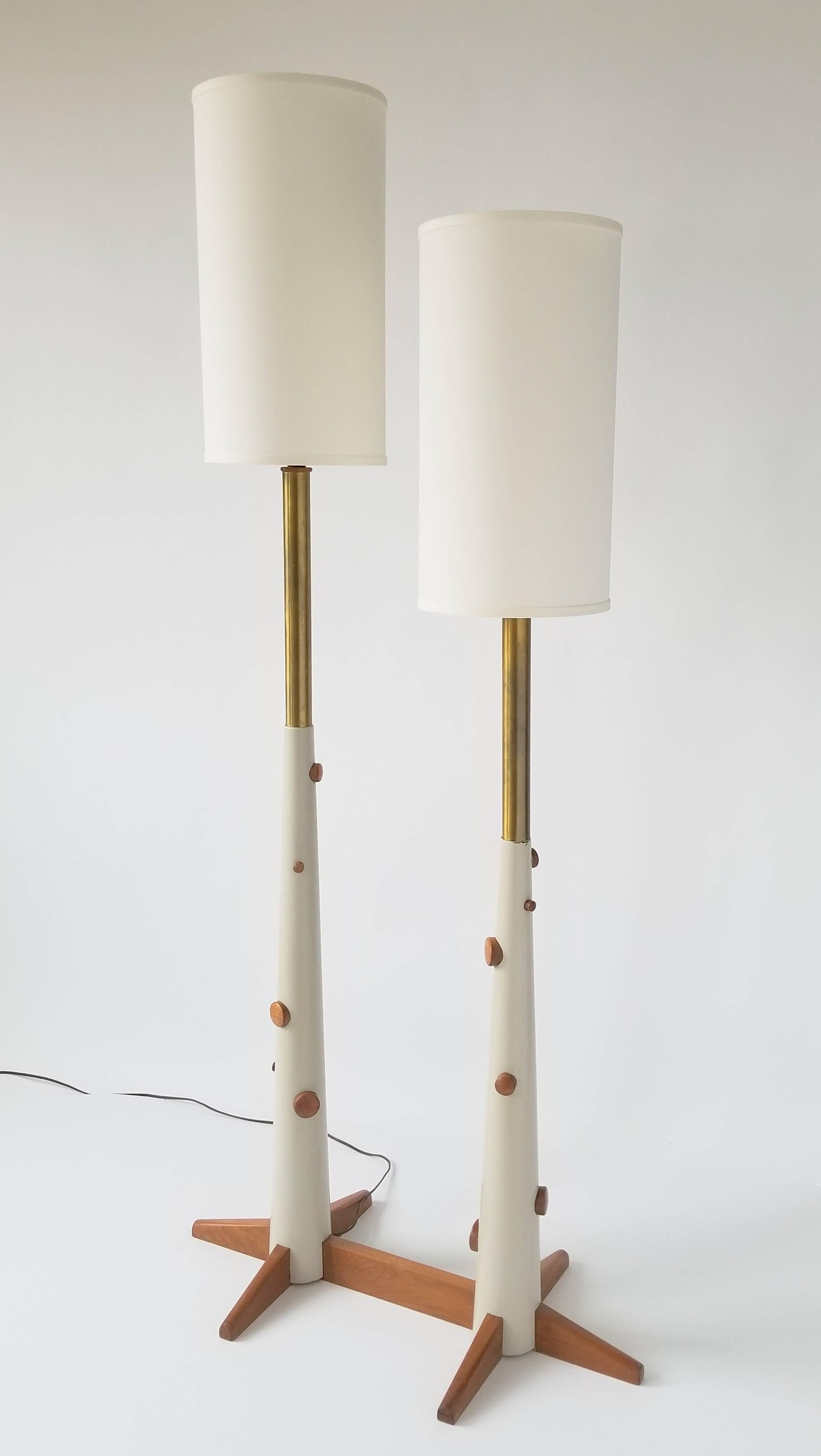 Unique twin stem floor lamp with  protruding  wood dot and base. 

The off-white lacquered conical pole are made of solid wood and are topped by a brass  tube.

Tallest side measure (with shade) 66.5 in. Shortest side 60 in.

Shade are new and where