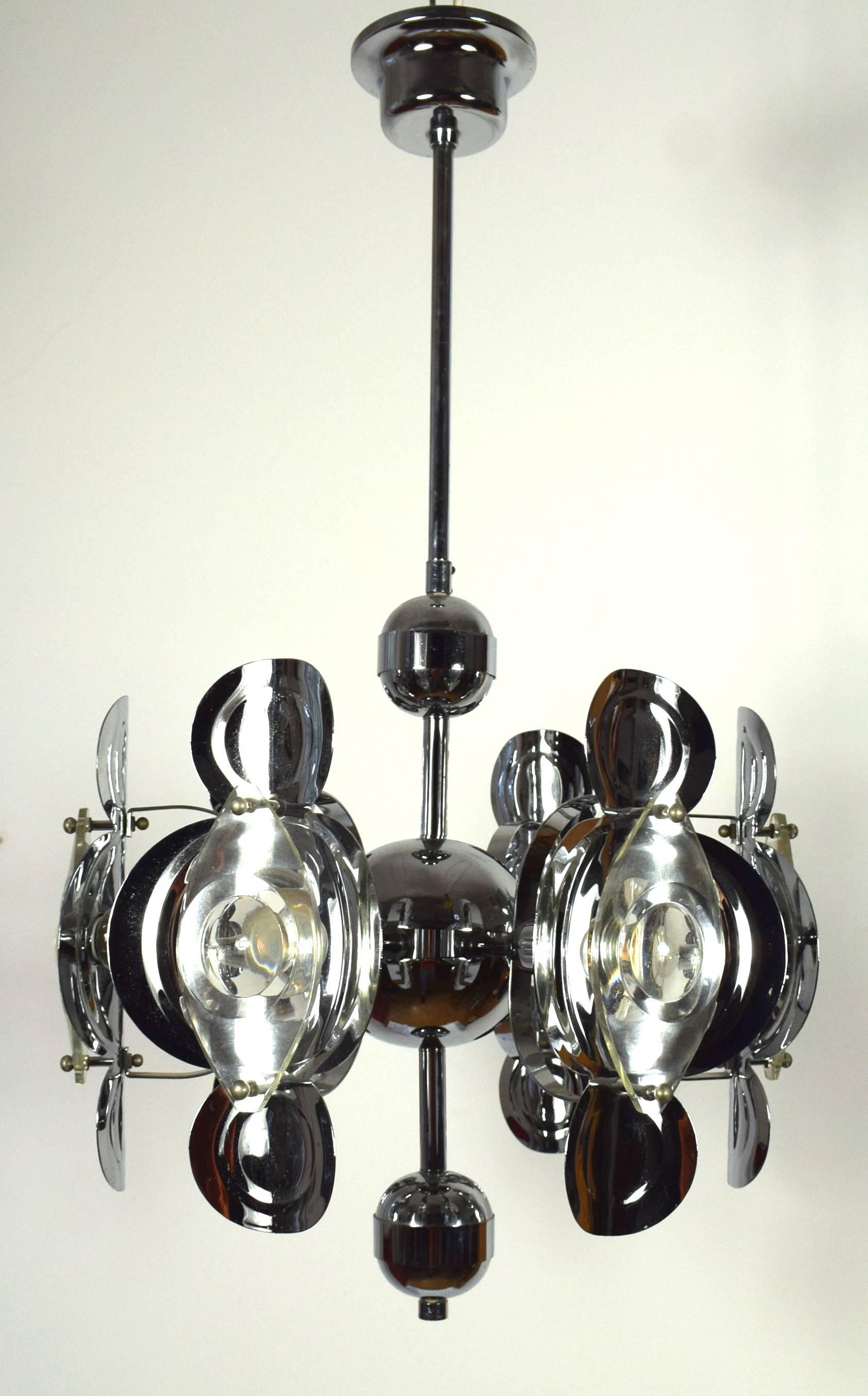 Italian, Mid-Century Gaetano Sciolari chandelier featuring a Sputnik frame and stepped canopy in the original chrome finish. Arge optic glass lenses are decoratively and functionally mounted on unusually shaped concave metal shields to serve as
