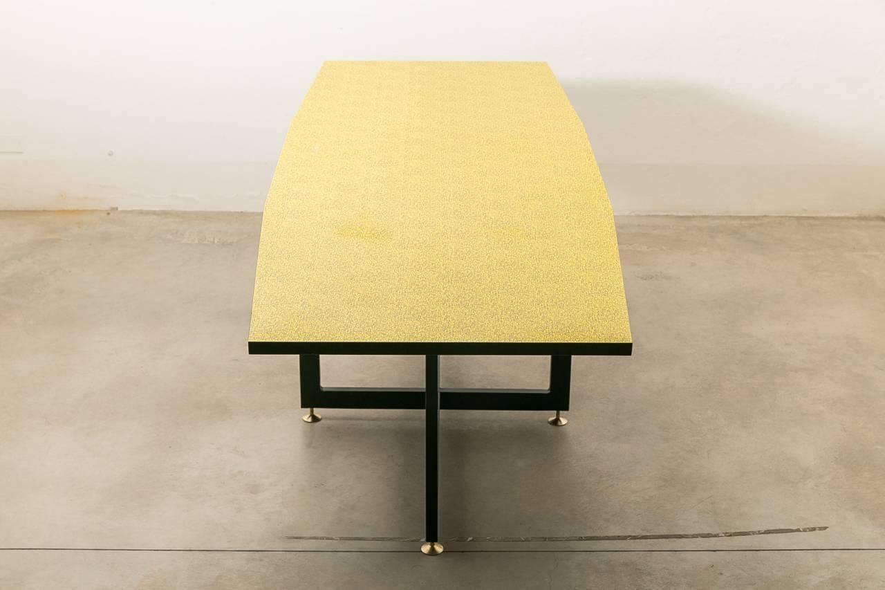 Mid-Century table with spectacular Formica top. The criss cross framed legs are made of black steel and finished with brass feet. The top Formica top is new.
  