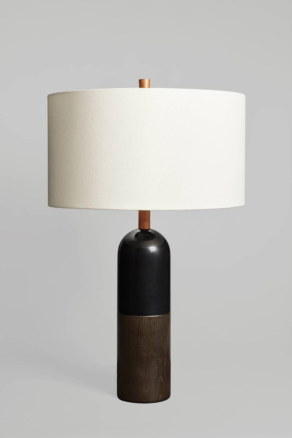 A large table lamp for an open space, the Tusten balances its substantial, geometric form with an expansive shade. The Tusten I has a base of dyed ash and ebonized maple, with cherry neck and finial. Sitting at 33” tall with 20” diameter trim less,