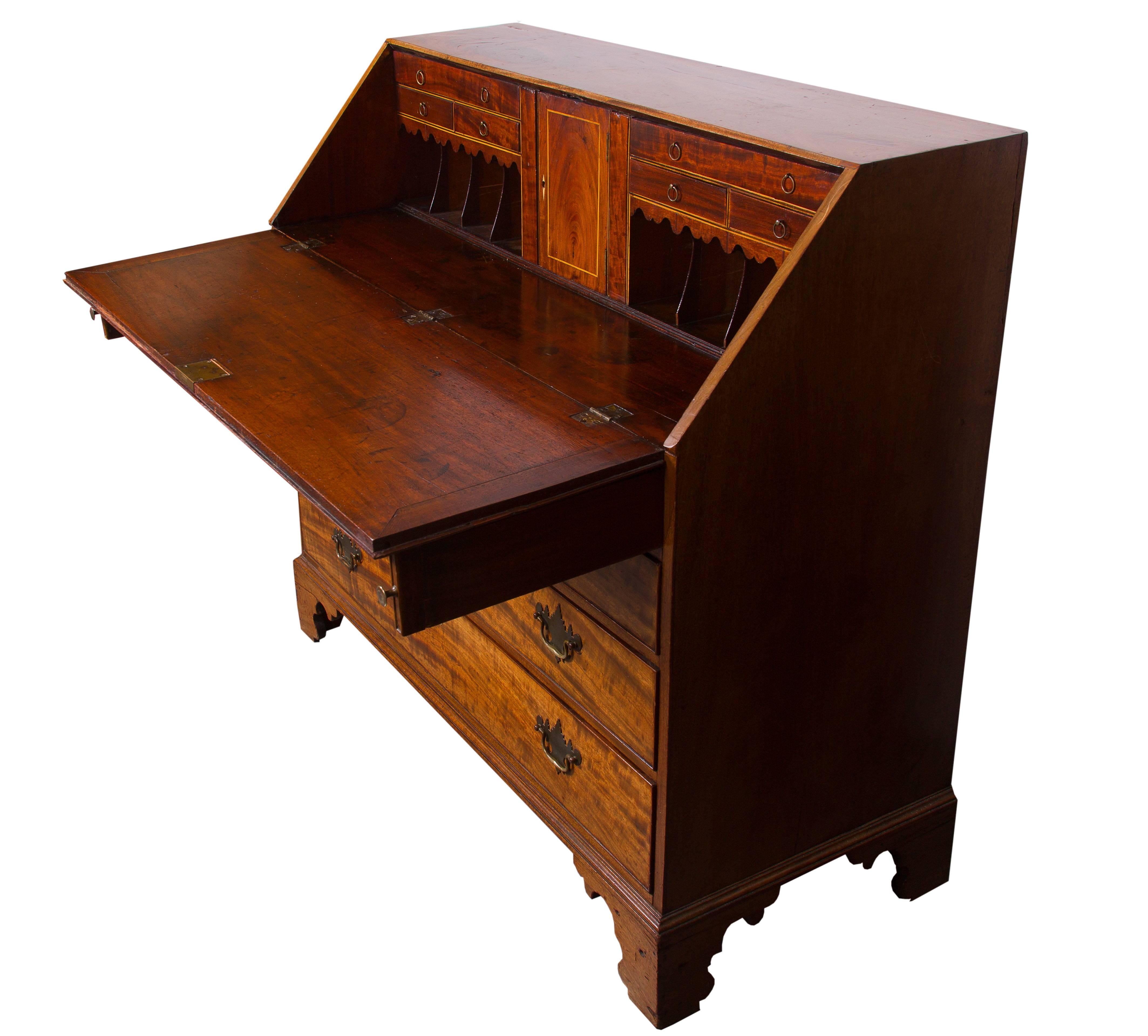 English mahogany slant front bureau. Drop front opening to reveal writing surface, miniature drawers and document compartments over four long graduated drawers with ivory escutcheons and raised on shaped feet.