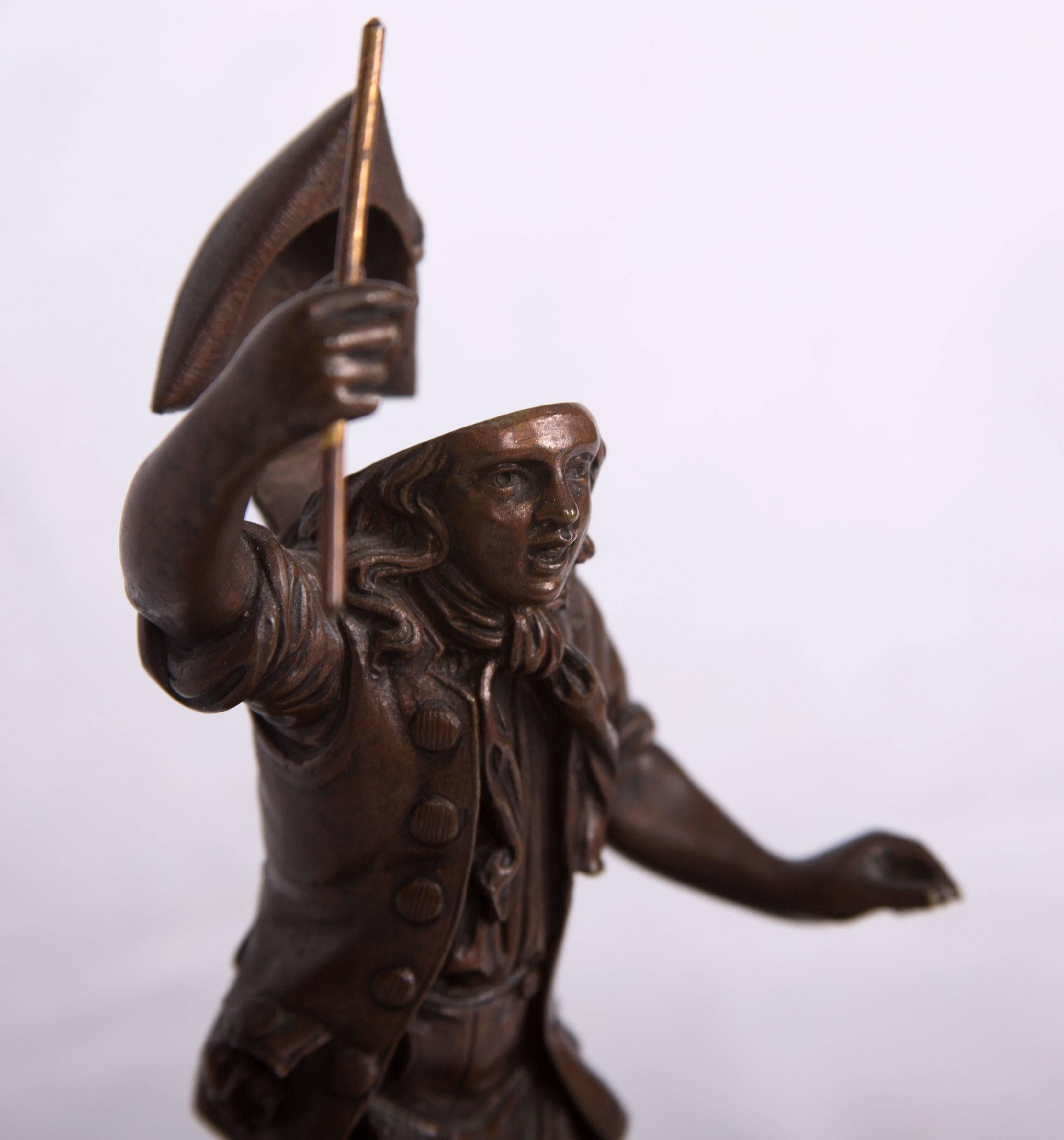This beautifully detailed French bronze and gilt inkwell shows a Revolutionary figure sounding an alarm of impending uprise while standing on a cobblestone street with a gilt metal document box and drum the top lifting and fitted with a porcelain