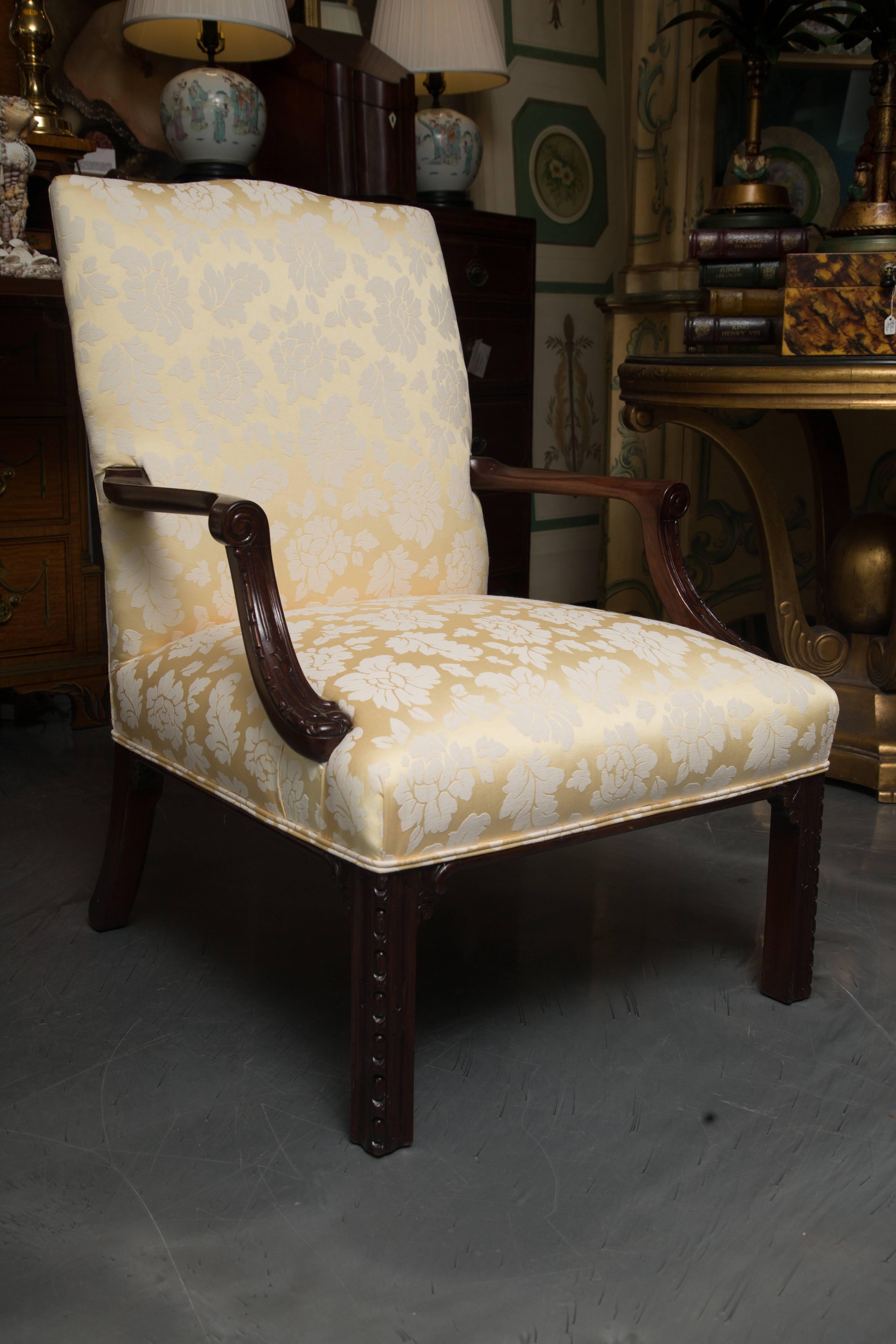 This is a stately and elegant pair of English mahogany library chairs with fully upholstered back and seat, flanked by out-scrolled arms and supported by straight rectangular legs, circa 19th century.