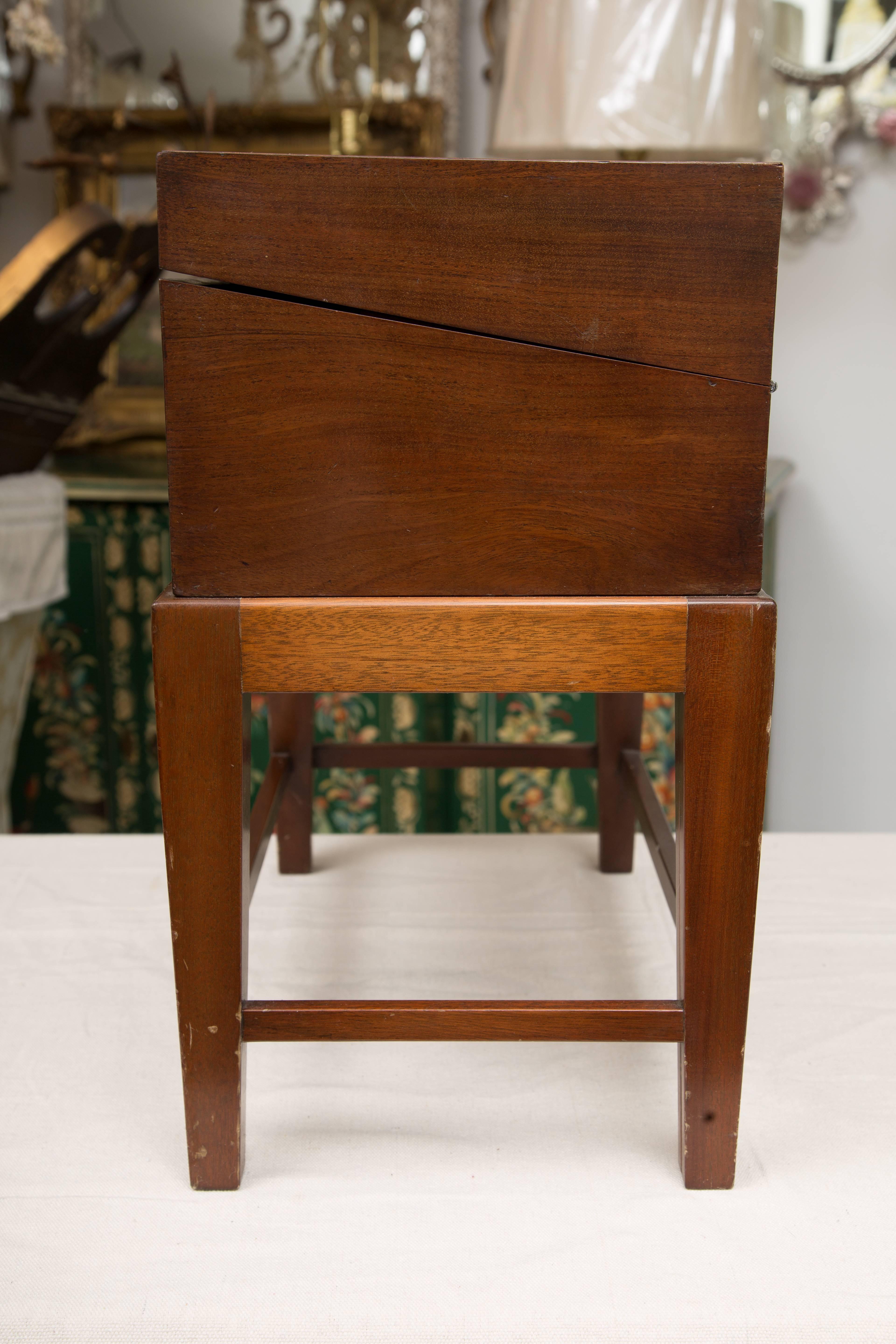 This is a traditional mahogany English mahogany with lap desk with satinwood banding, opening to reveal inkwells, interior drawers and writing surface, fitted to later stand, circa 1800 (box).