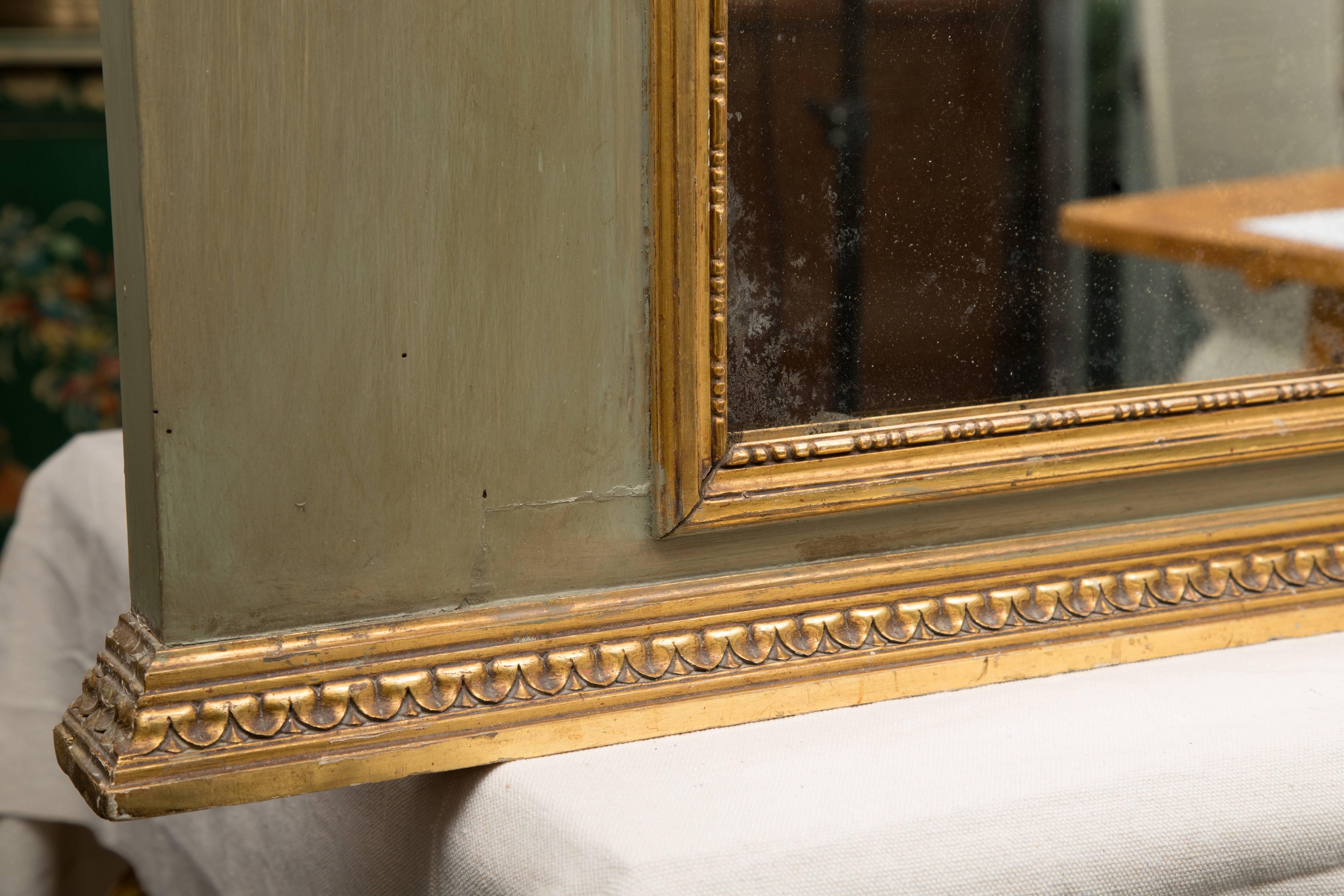 This French trumeau has a mirror plate surrounded by a green painted frame, the sides heightened with gilt bows and trailing laurel leaves. The gilt cornice is over a flowing gilt bow, 20th century.