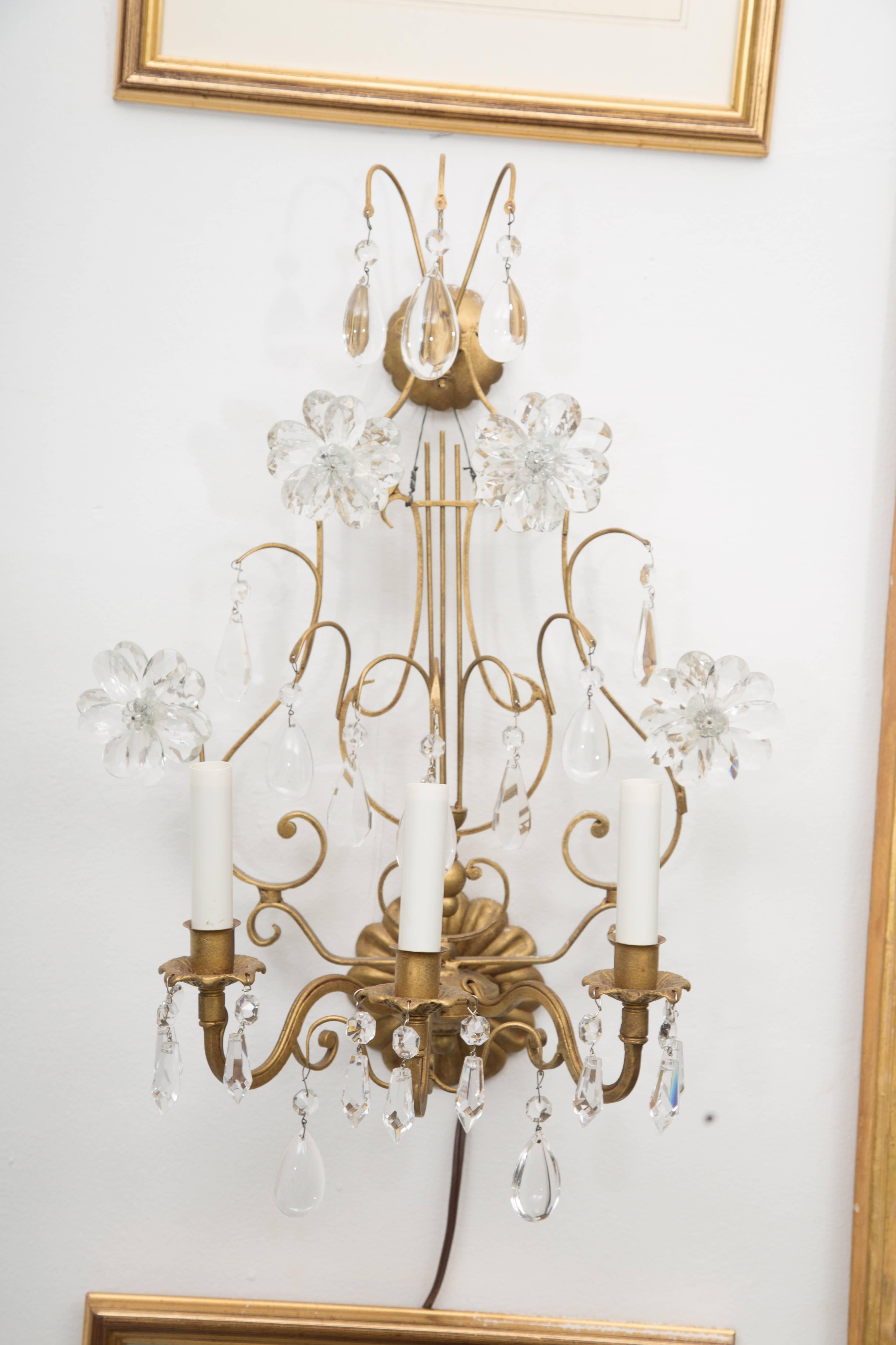 This romantic pair of lyre-form Italian electrified gilt metal sconces is softened by the application of glass flower-heads and glass prisms, 20th century.